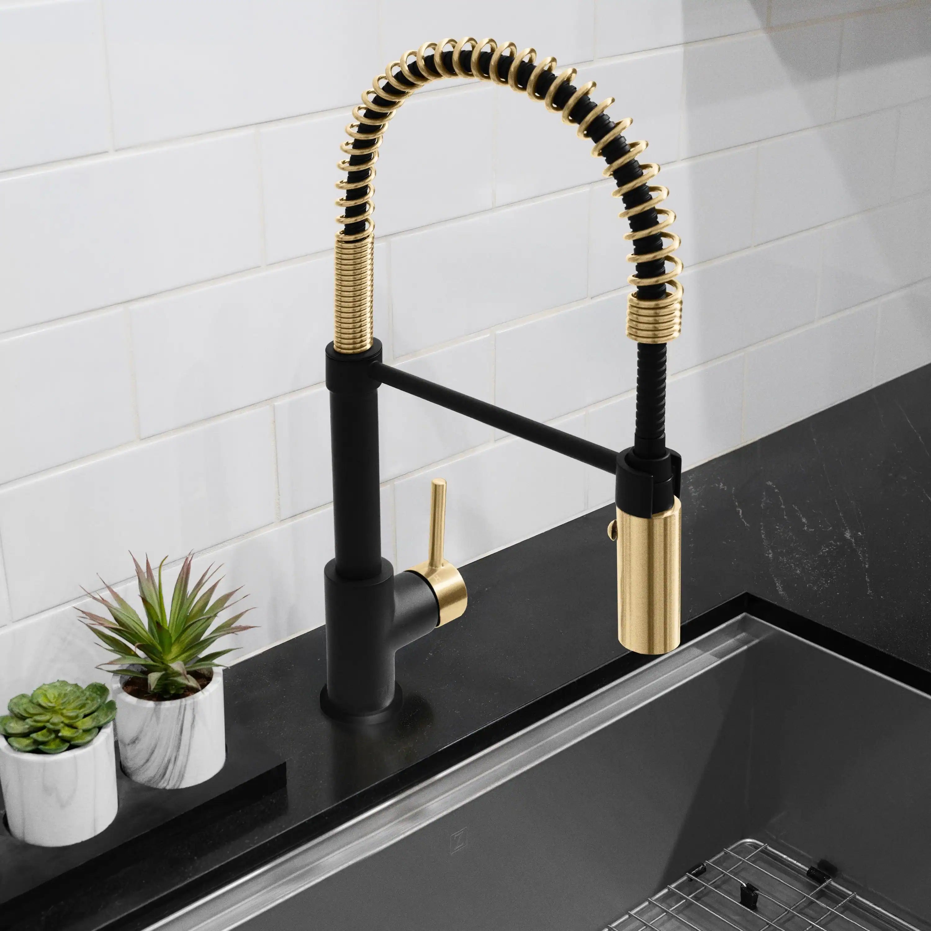 Matte black and champagne bronze pull-down kitchen faucet over sink with coiled spring hose