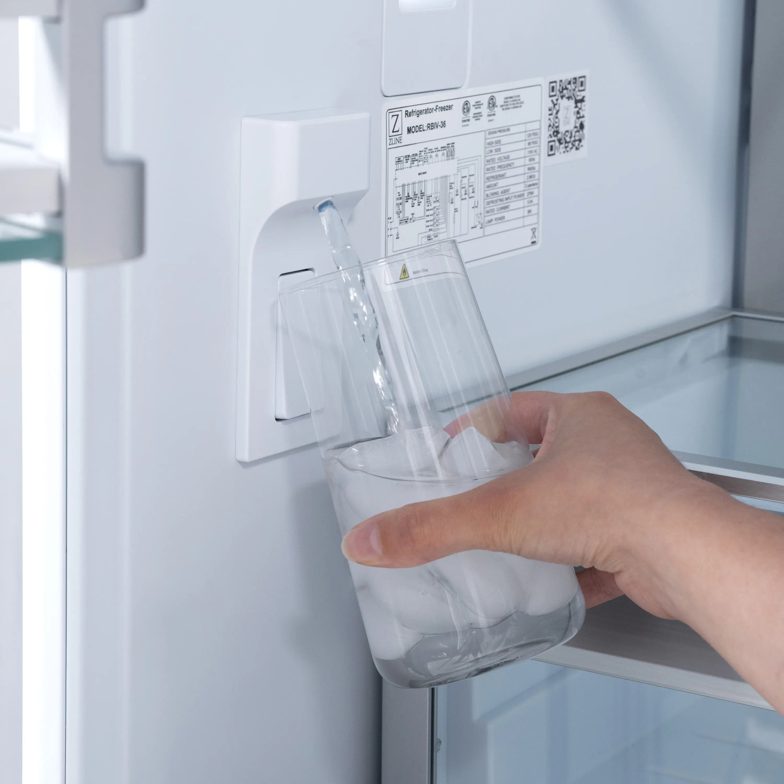 Water dispenser with hand holding a clear cup inside the refrigerator door