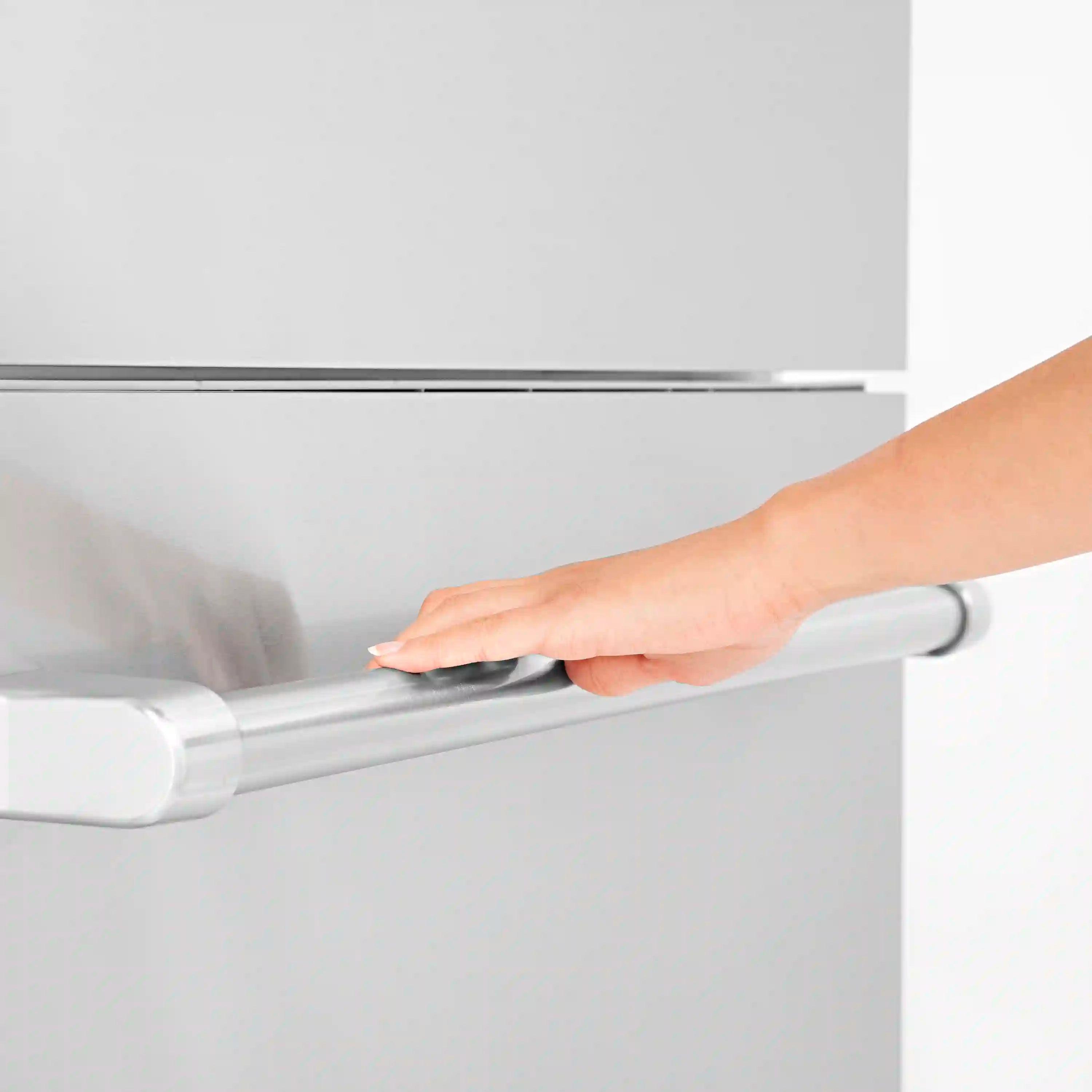 White refrigerator door handle being pulled by a hand
