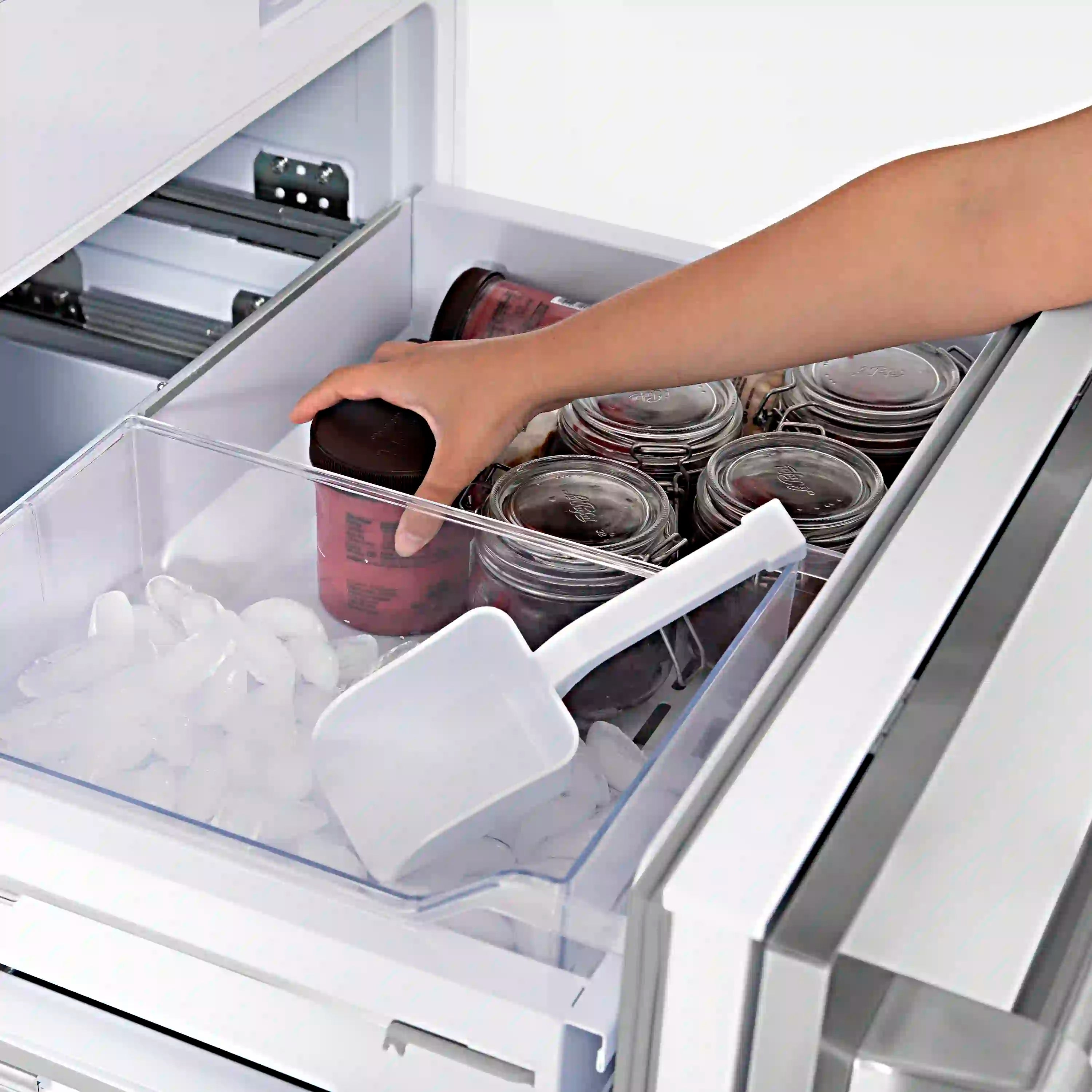 French door refrigerator with open drawer stocked with jars and food items