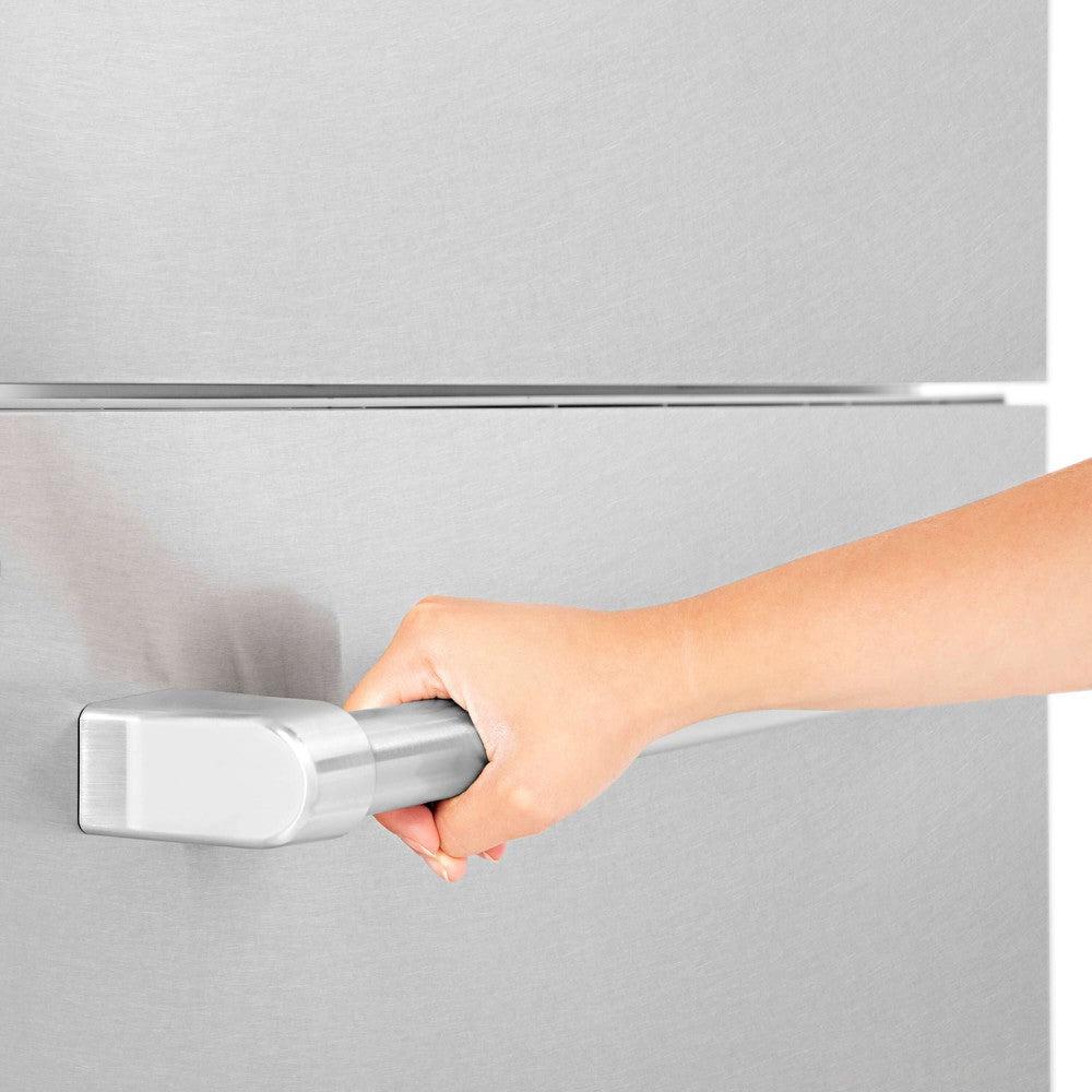 Person gripping a stainless steel refrigerator panel handle bar with thumb lever