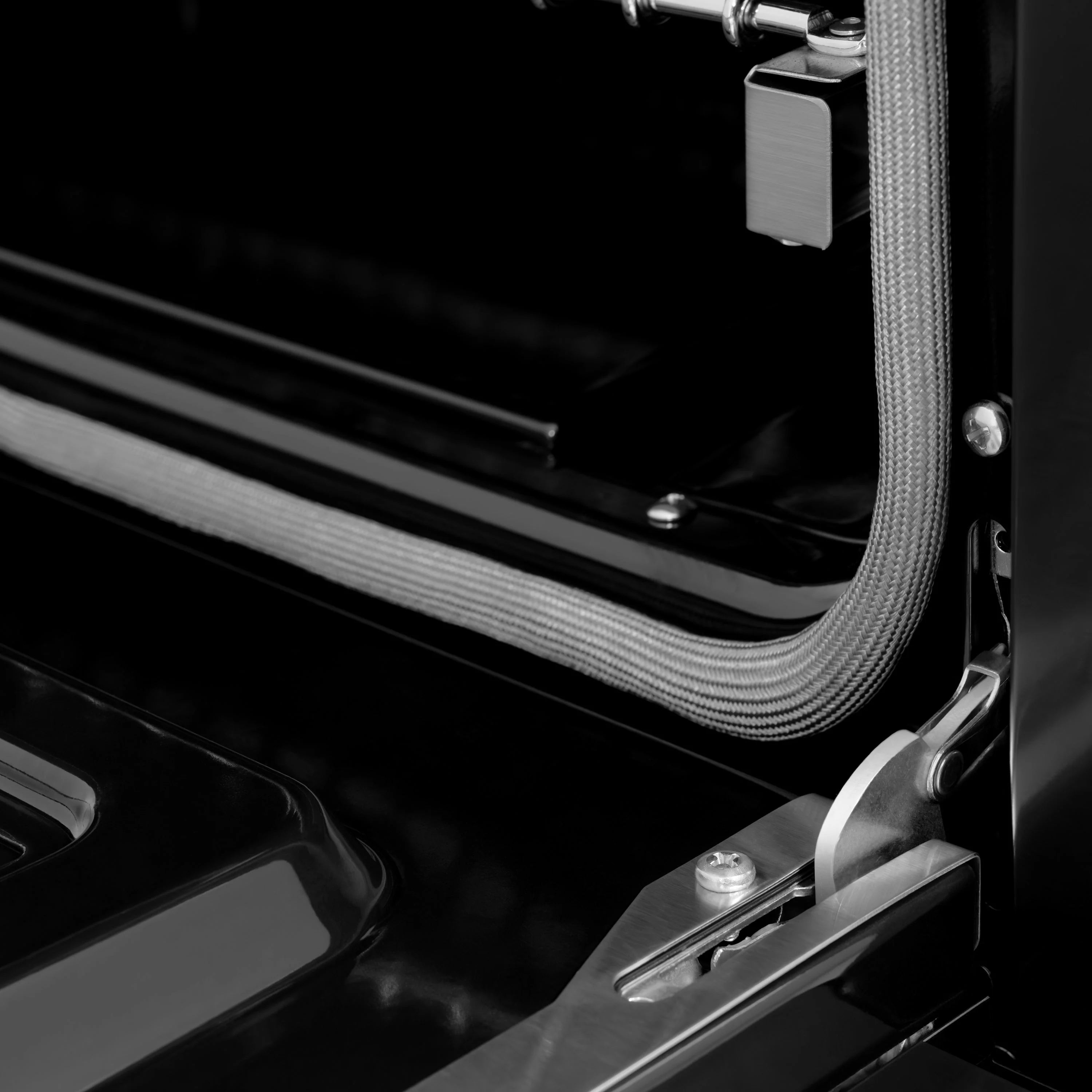Gas range oven door handle and hinge area with braided flex gas line
