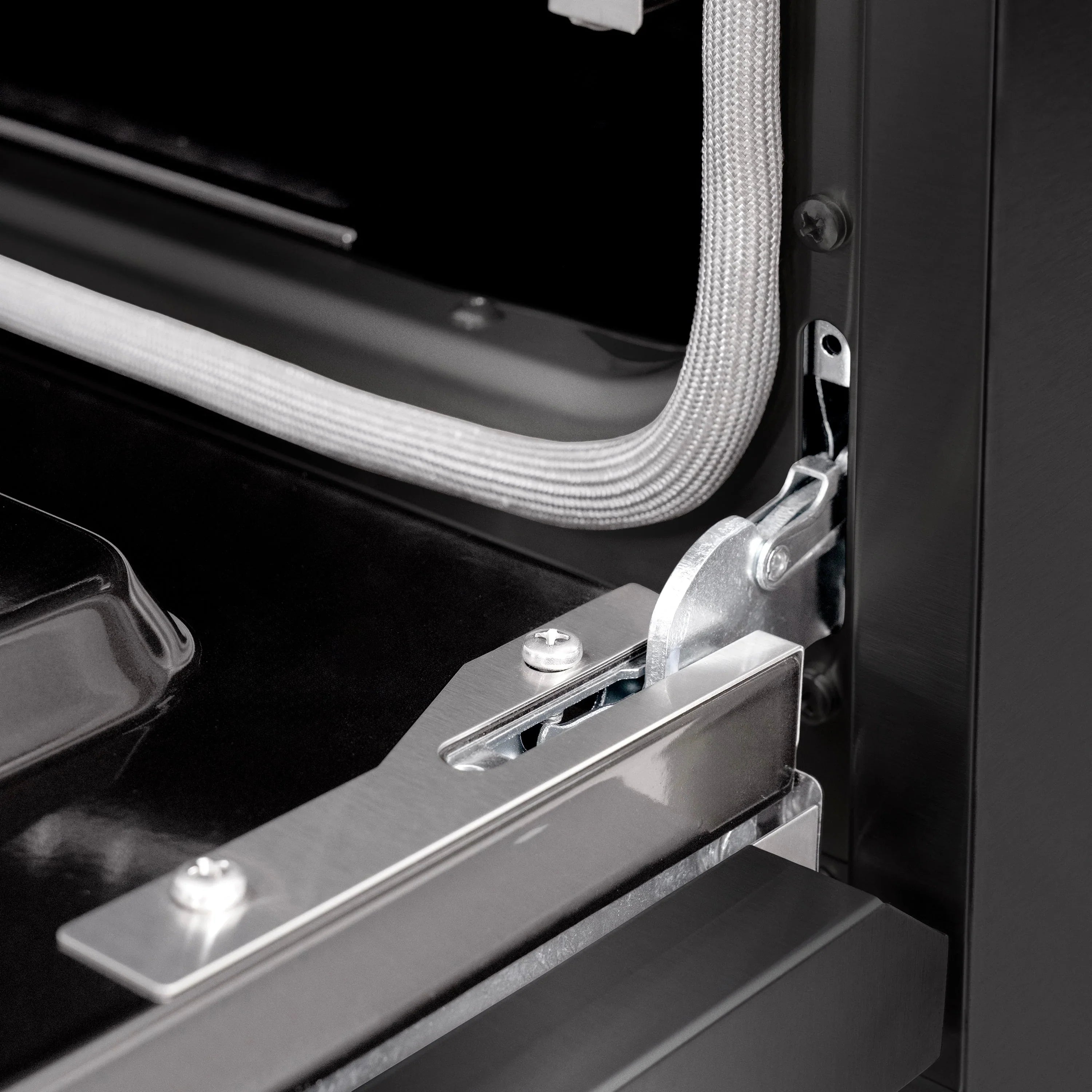 Close-up of black oven door handle with metal latch and mounting hardware
