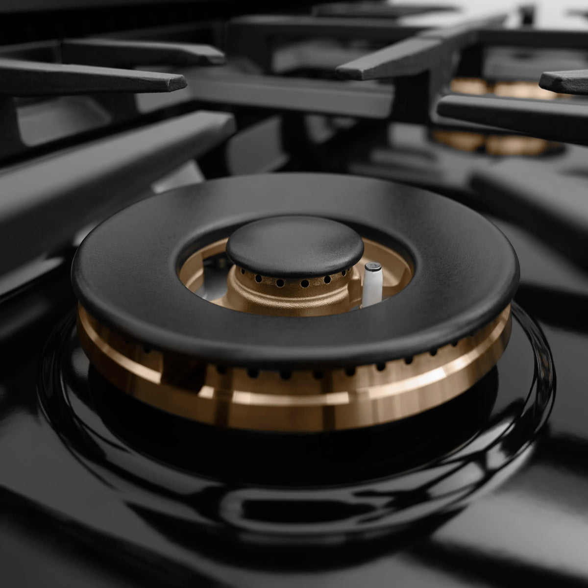 Single gas burner with black cap and brass inner ring on a black cooktop