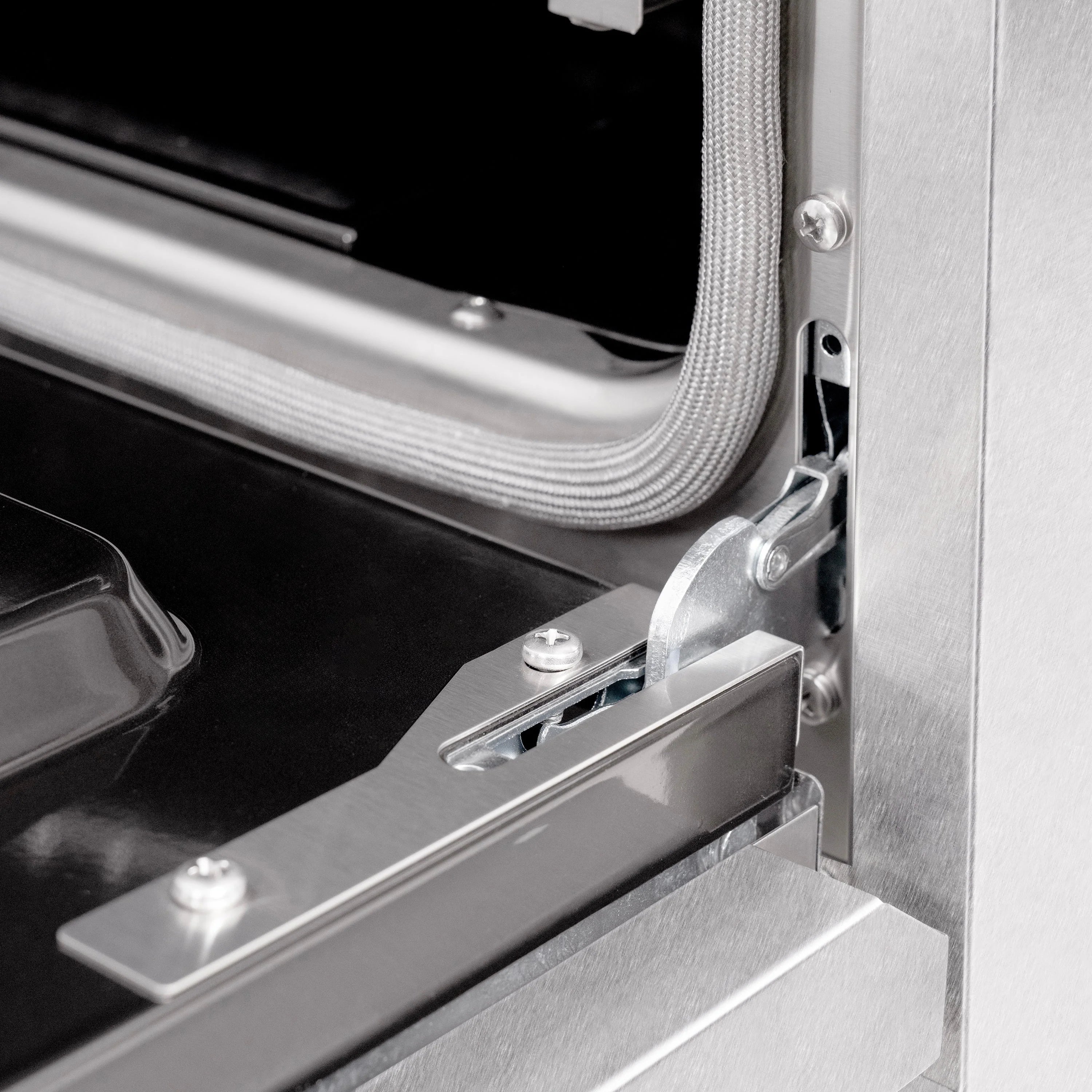 Range side drawer latch with metal guide and braided cable near oven opening