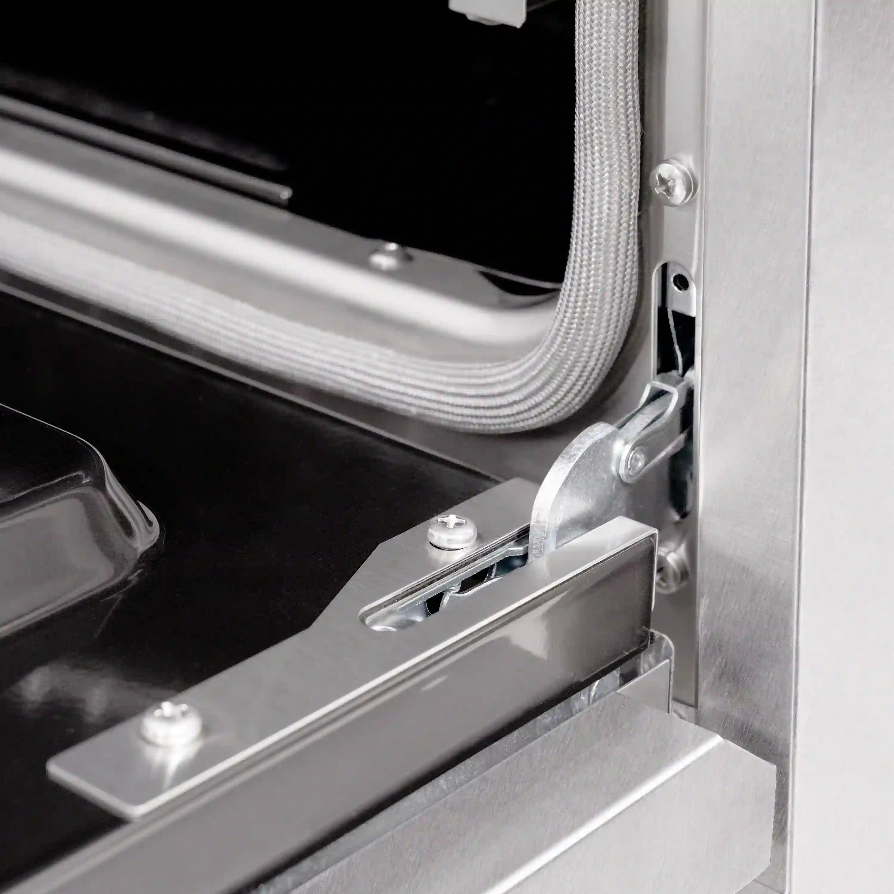 Oven door latch and hinge area with braided gasket and satin stainless steel frame