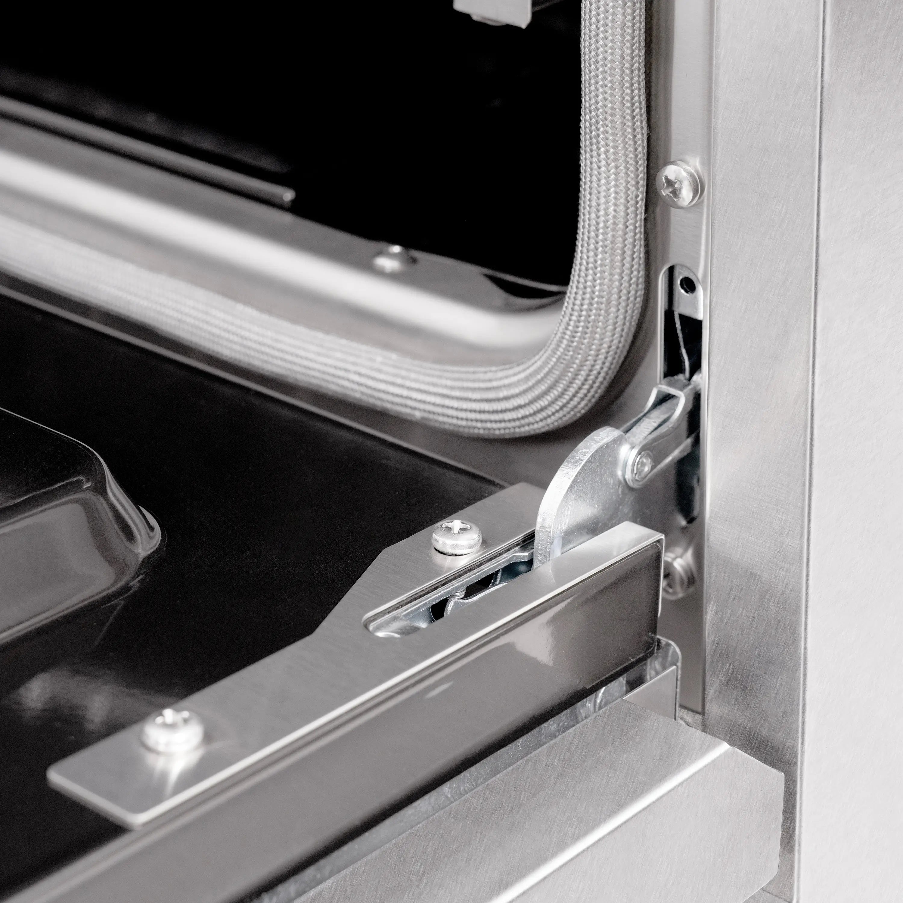 Stainless oven handle and hinge bracket detail on a gas range