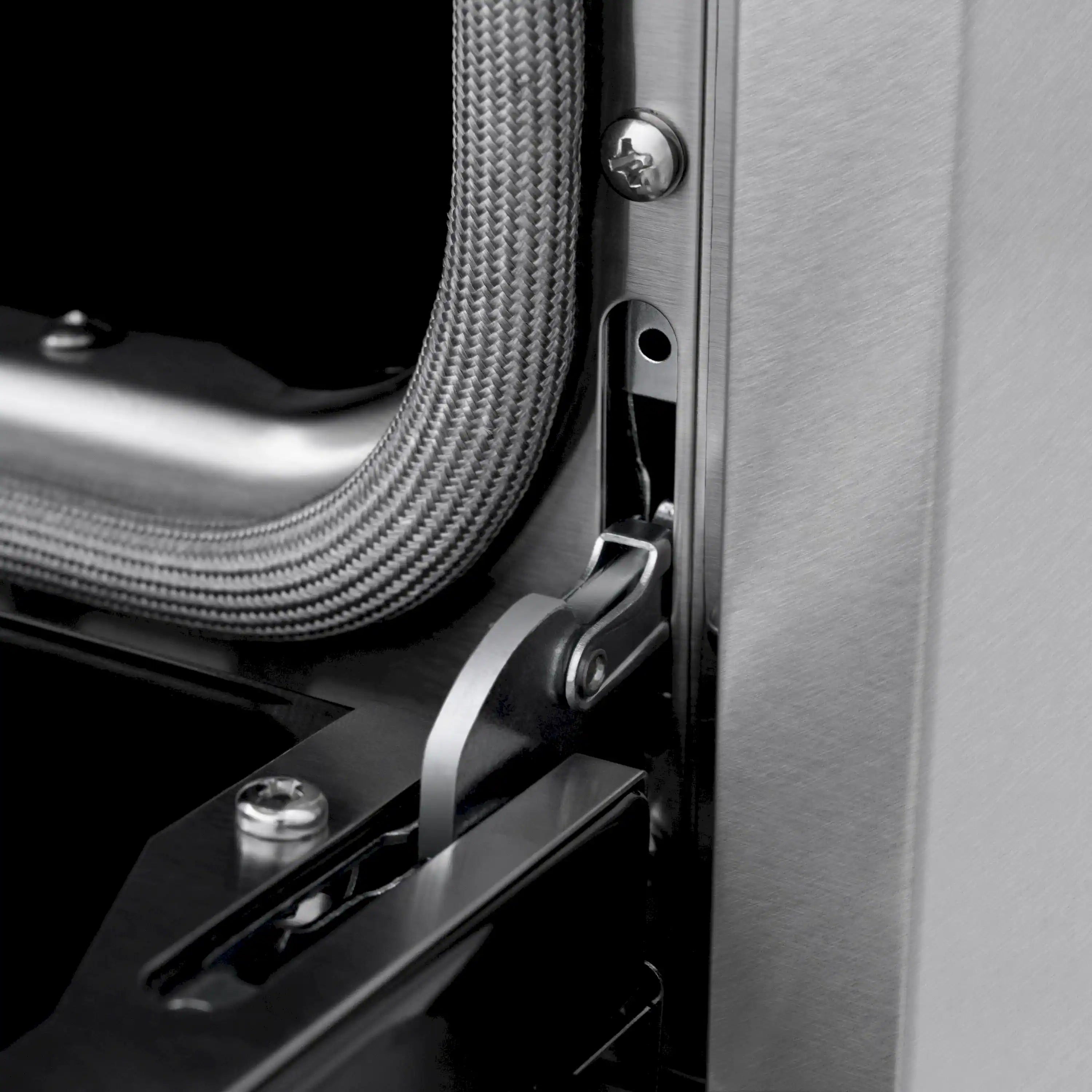 Close-up of stainless range side panel with black oven handle and gas hose