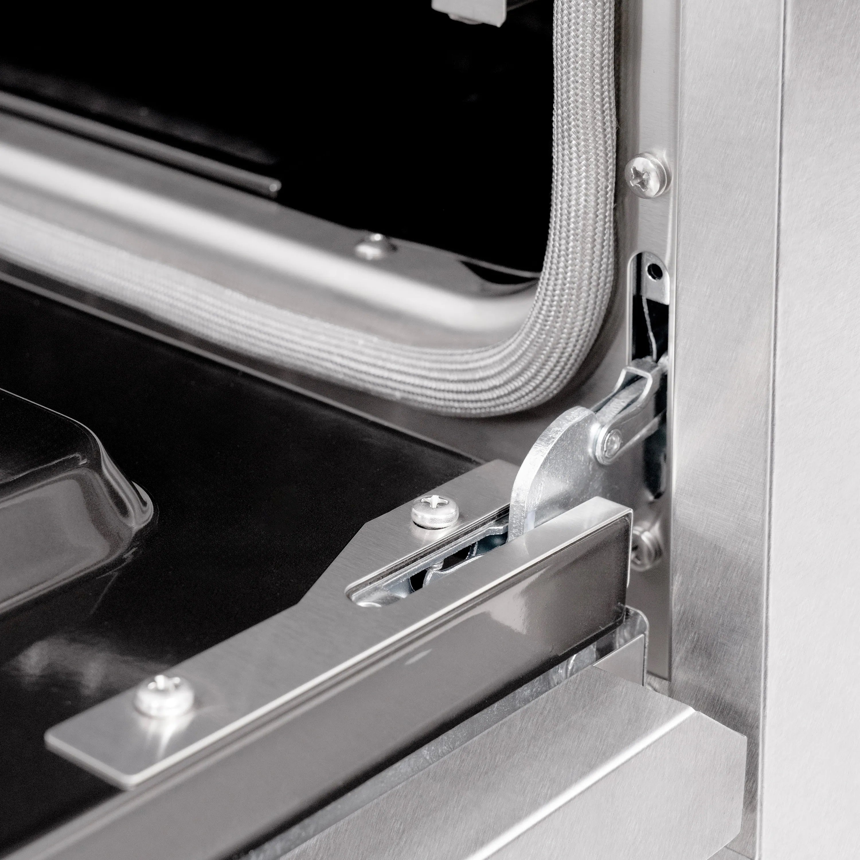 Close-up of gas oven door hinge and stainless handle hardware