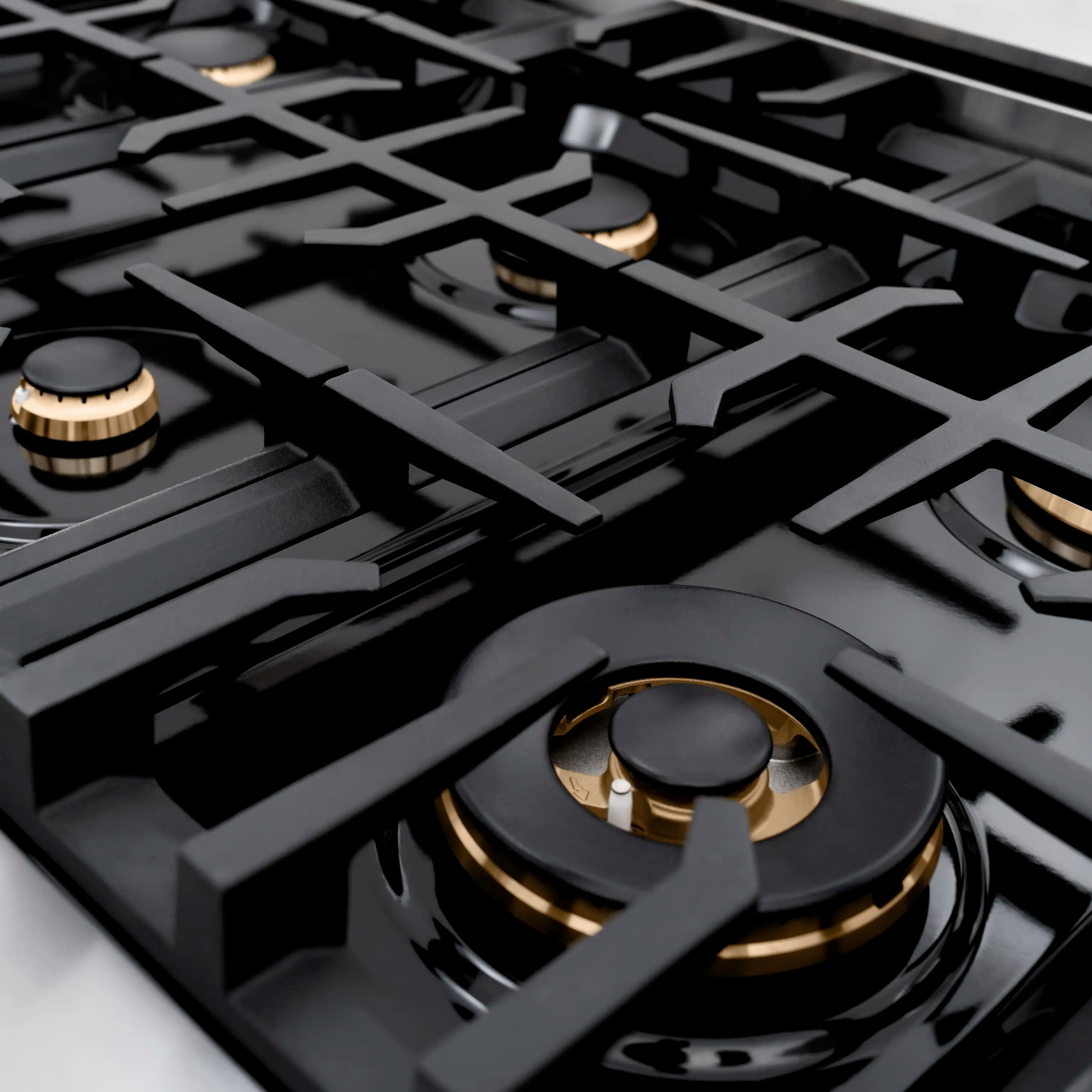 Black gas cooktop grates with brass-trim burner knobs and cast burner caps