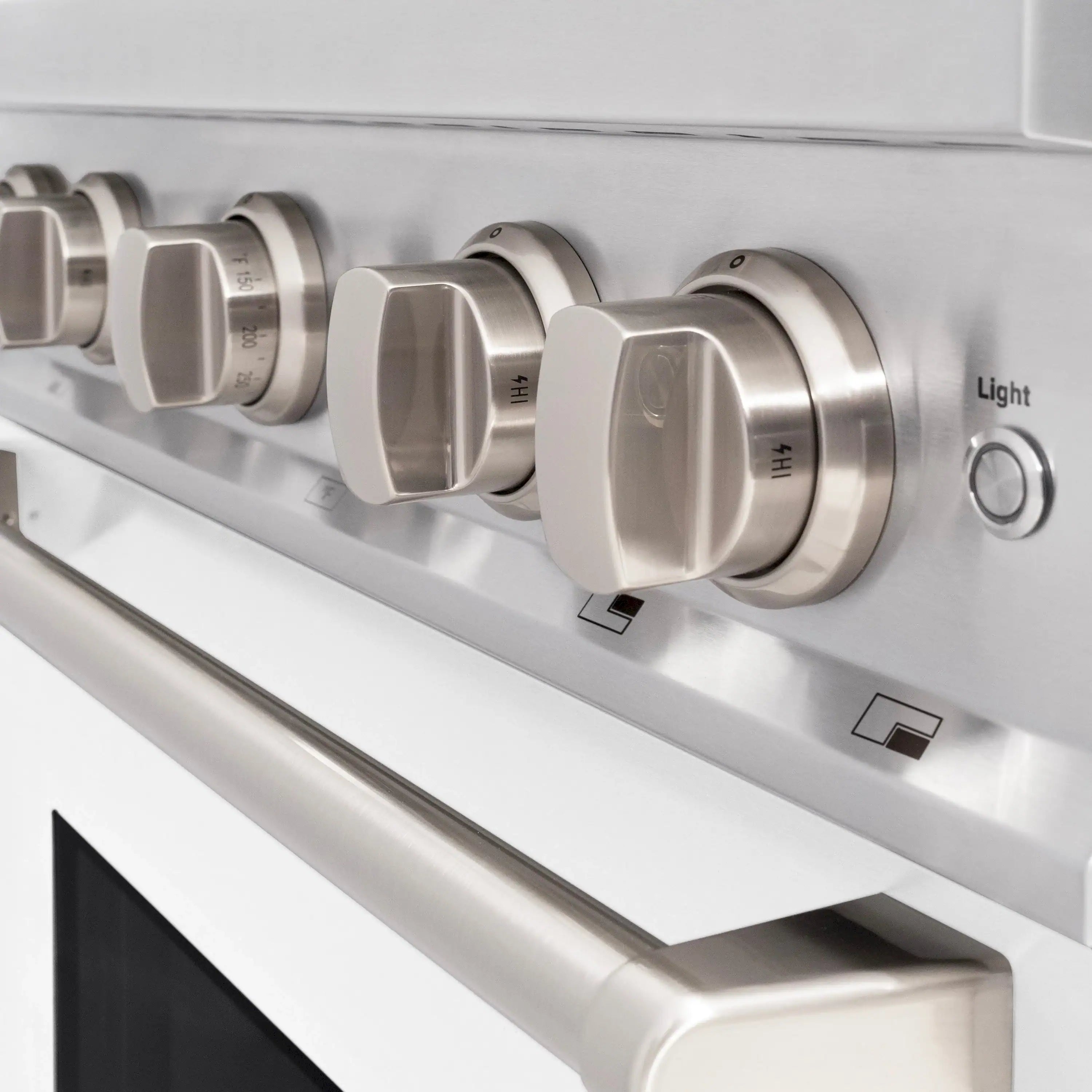 Stainless gas range control knobs and burner controls on white matte cooktop panel