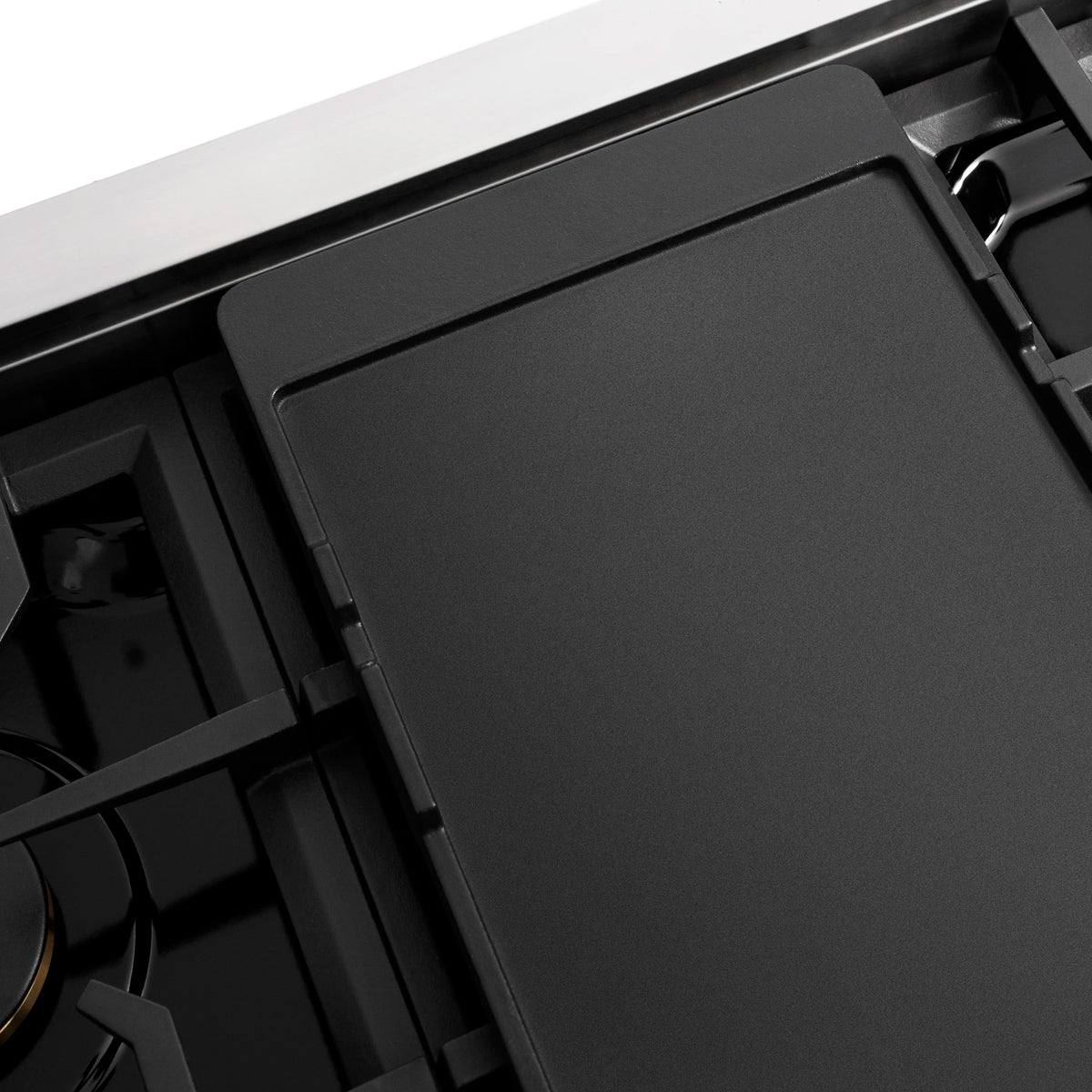 Black flat griddle pan insert in black gas stovetop, close-up