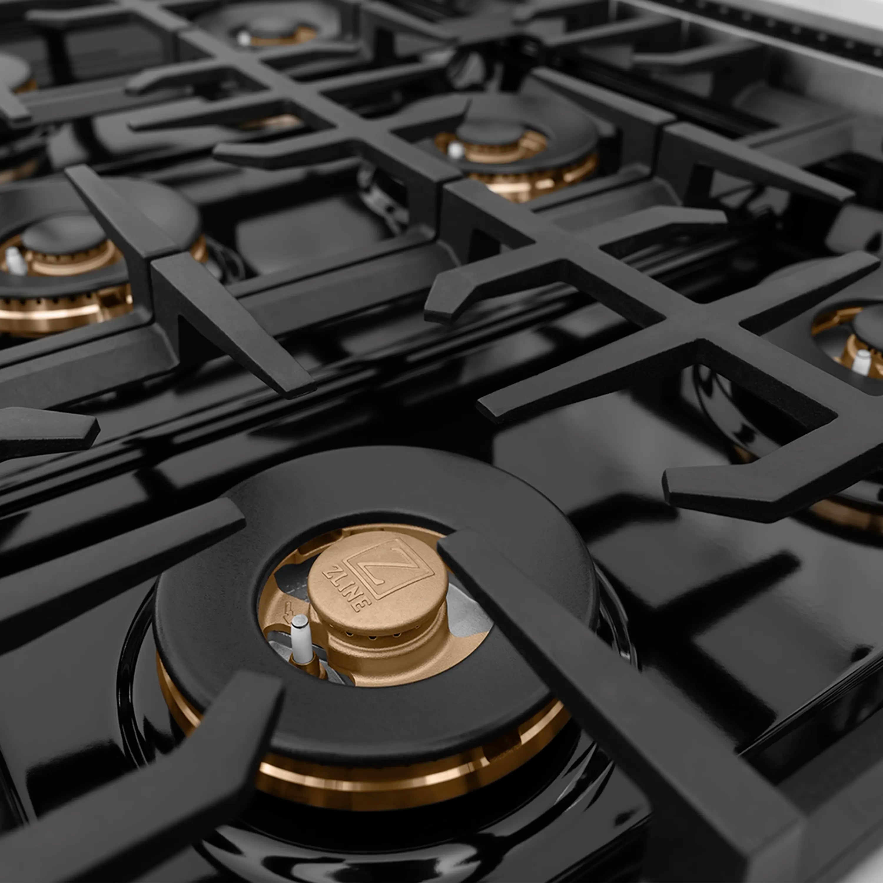 Multiple brass-and-black burners on a glossy black gas cooktop surface