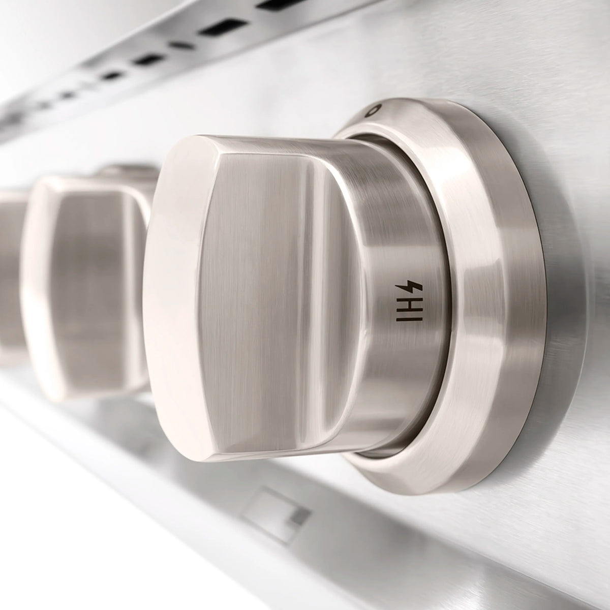Stainless steel gas cooktop control knob with brushed metal finish, close-up