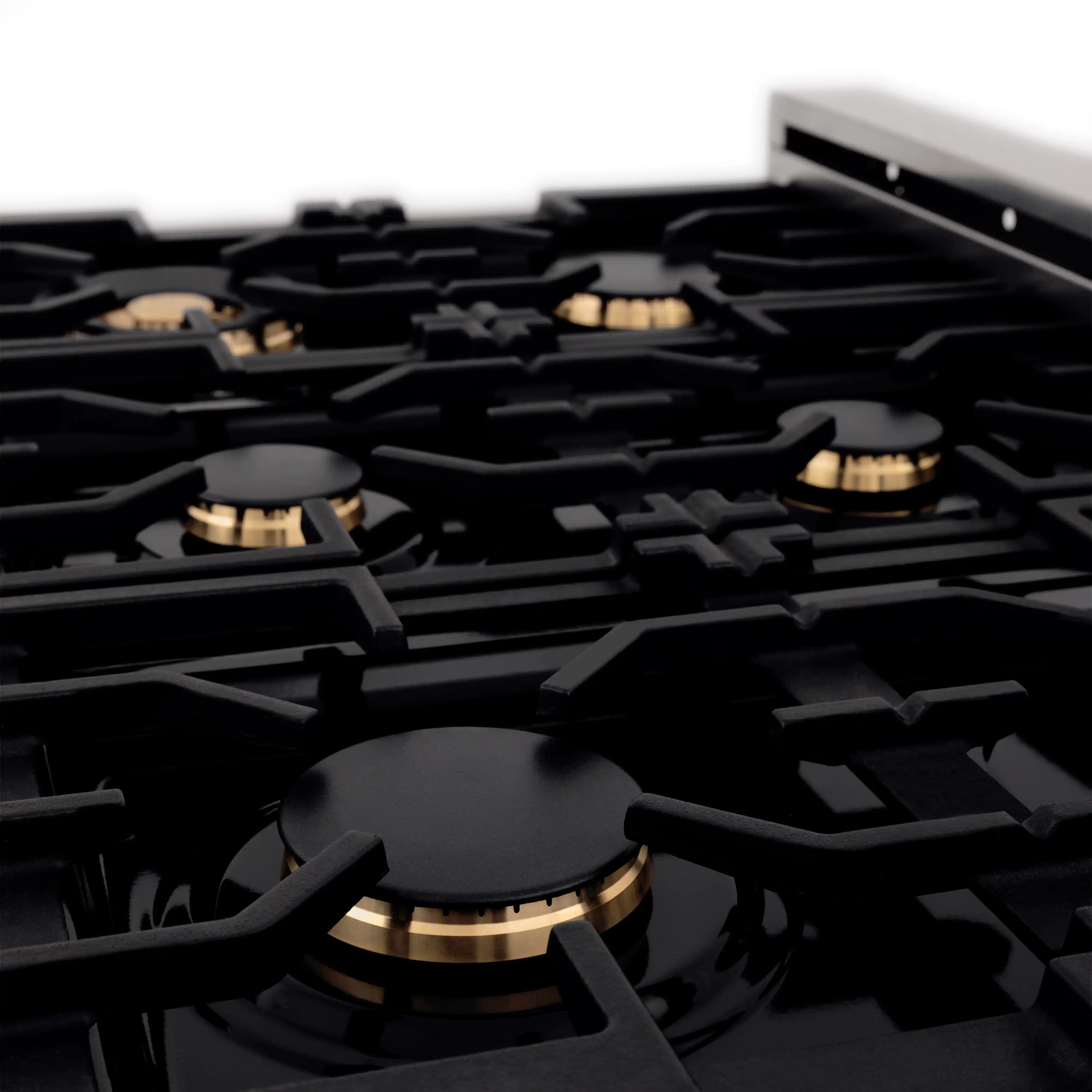 Gas cooktop with black burner grates and gold-toned burner caps