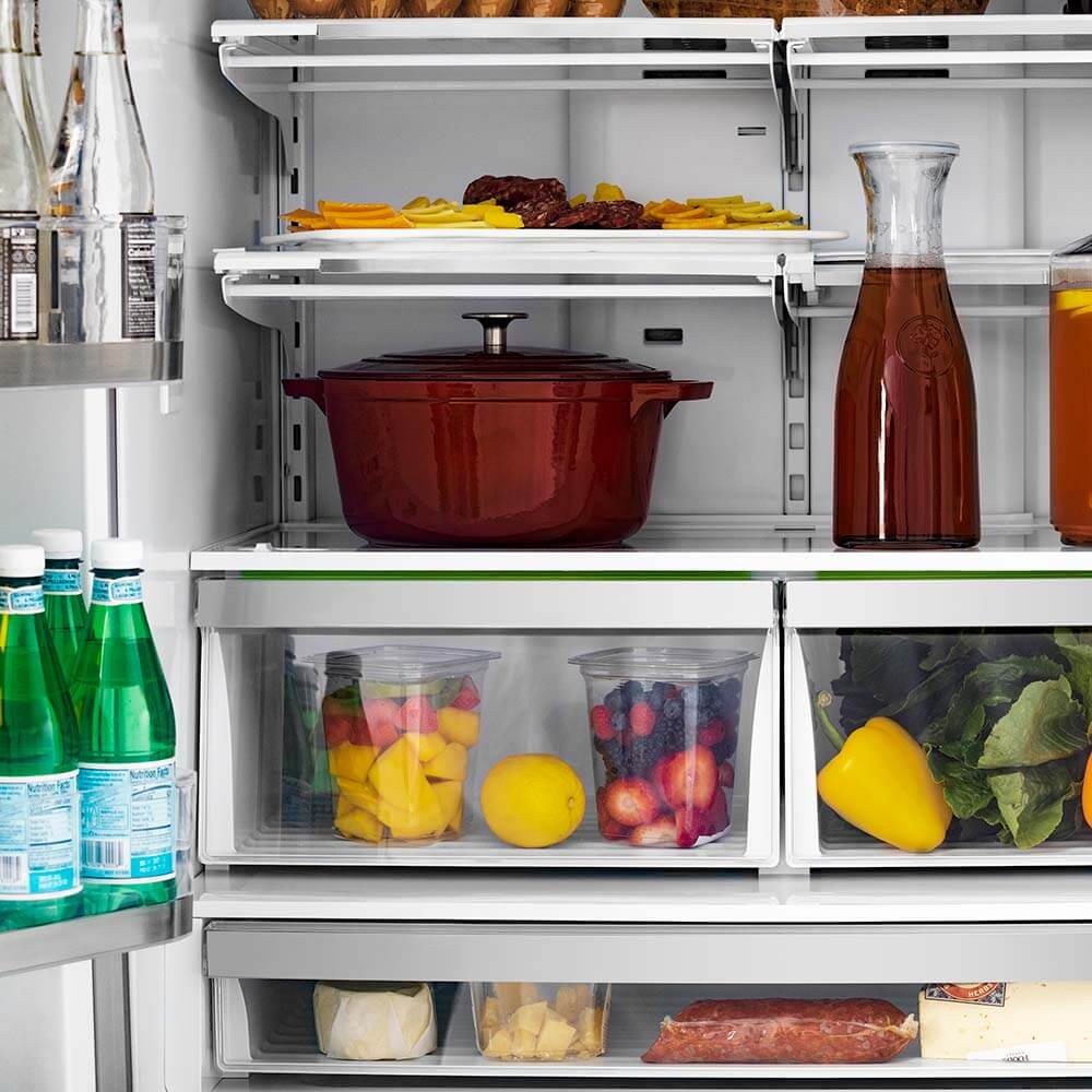 Open French door refrigerator with clear shelves, bins, and food items