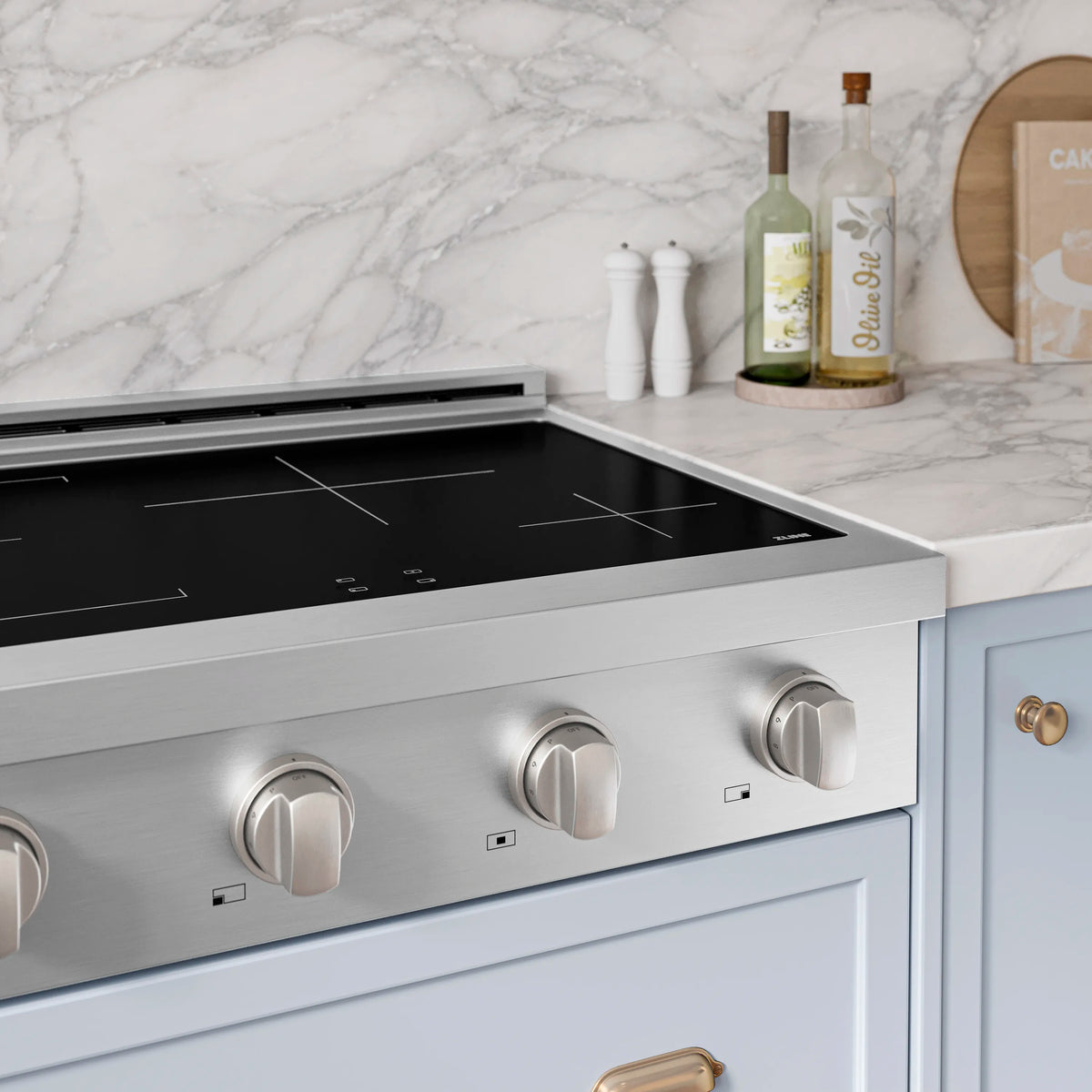 Stainless steel induction rangetop with black glass top and three visible control knobs