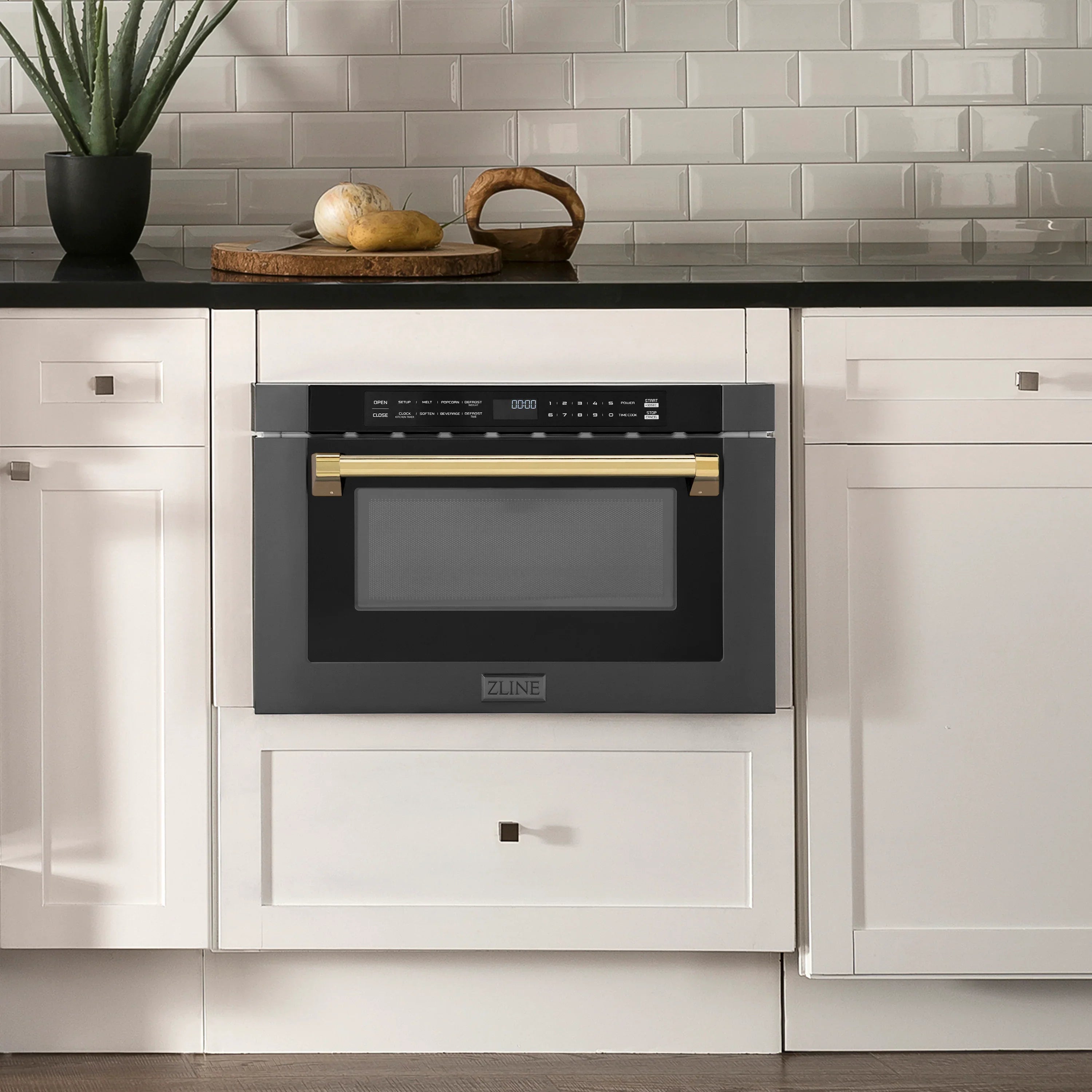 Built-in black stainless microwave drawer with gold handle in a kitchen cabinet