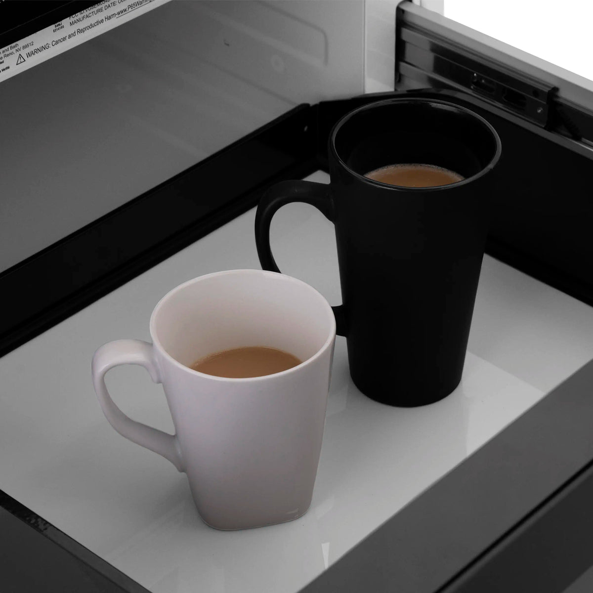 Open microwave drawer with black door frame and white interior