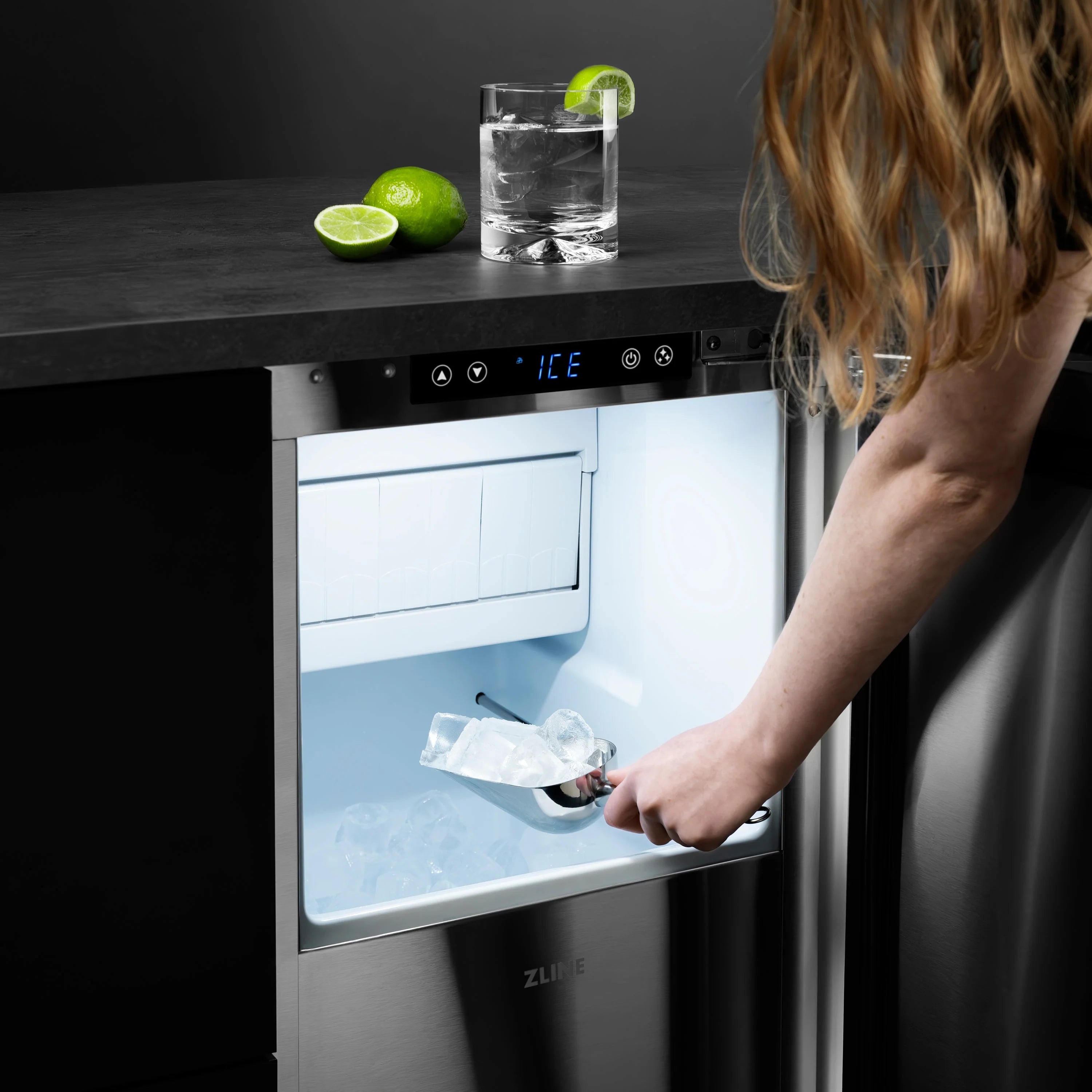 Ice maker with door open and hand filling a glass with ice