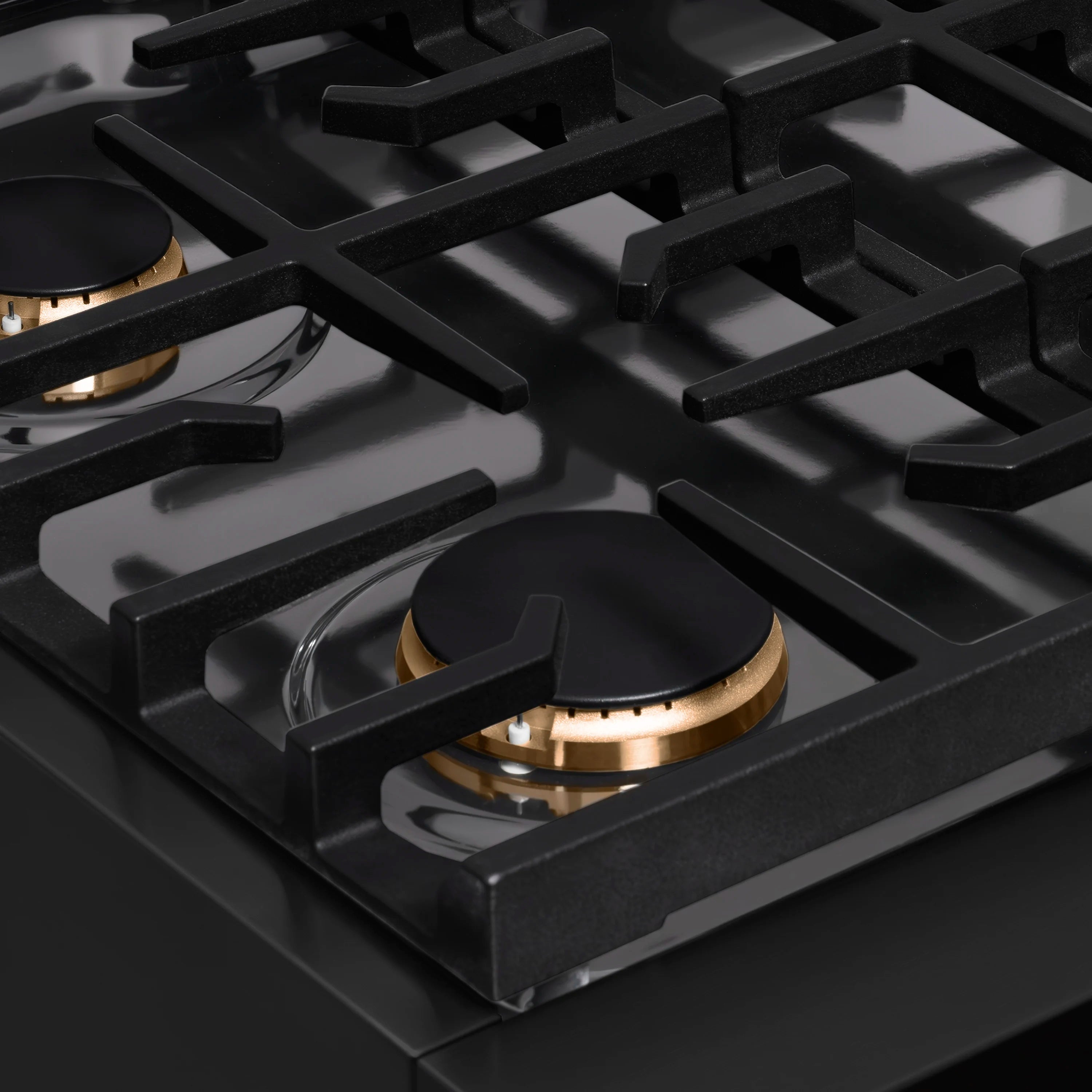 Close-up of black porcelain cooktop with cast burner grates and bronze burner cap
