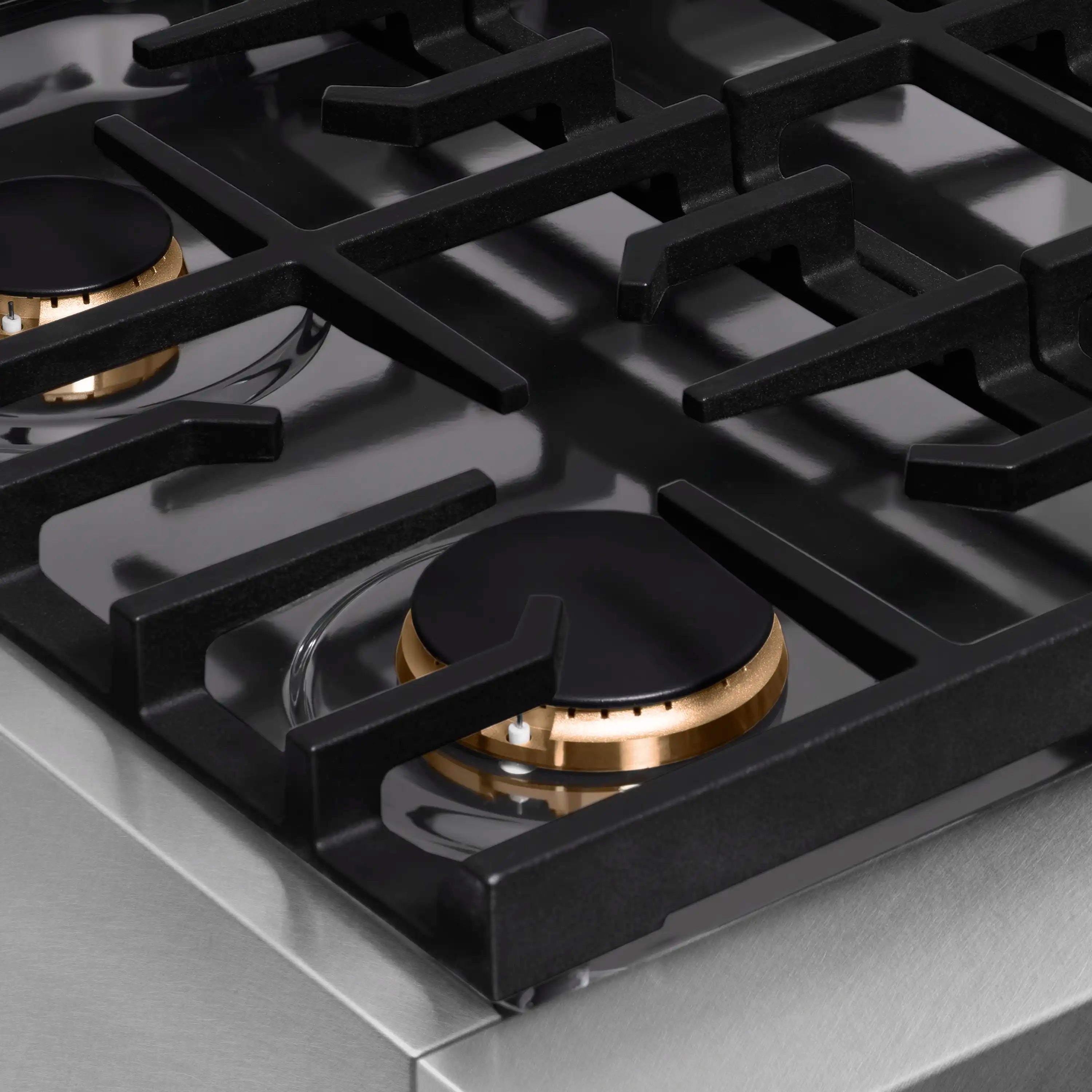 Single burner on black cast-iron grate with gold ring trim on stainless cooktop