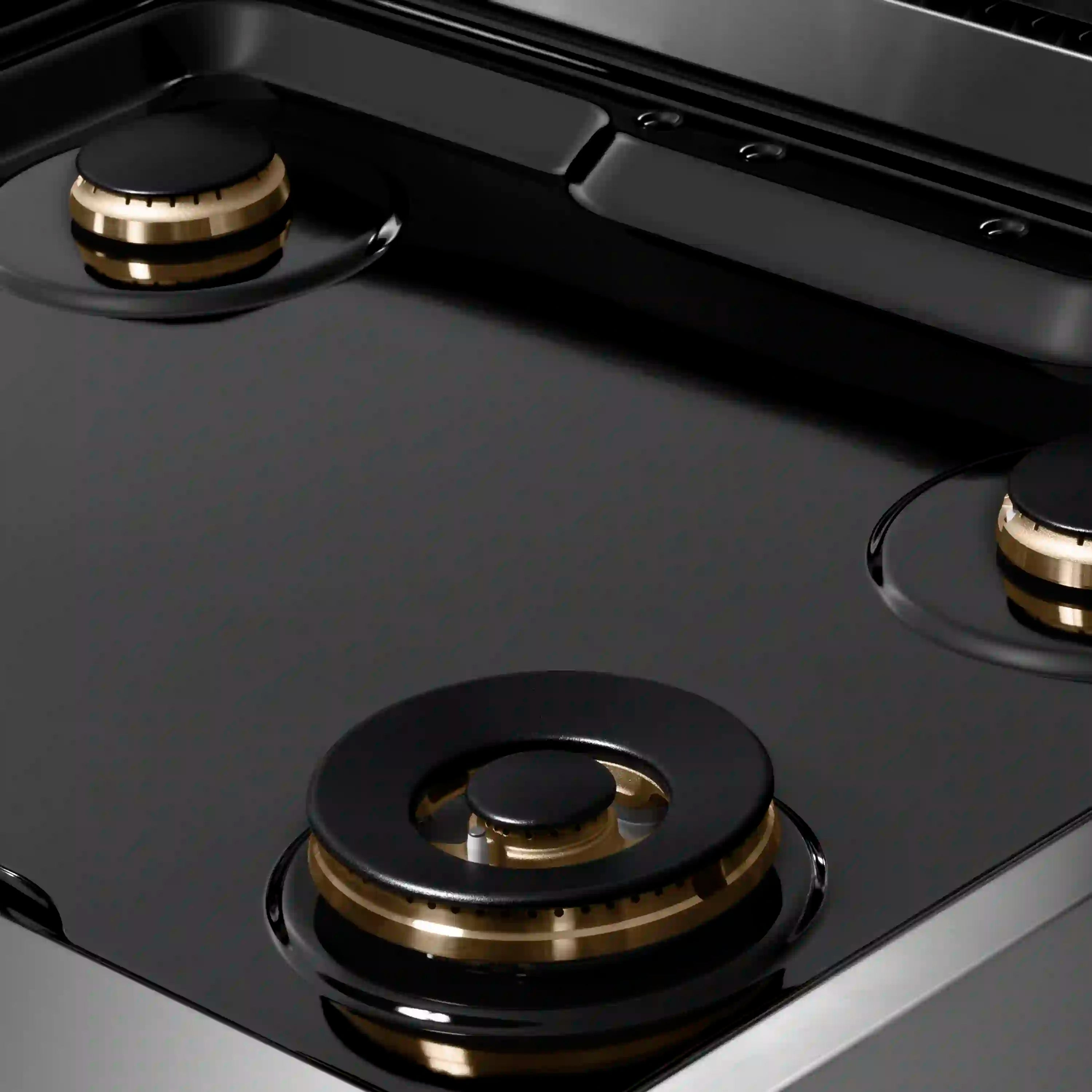 Gas rangetop burner with black cap and brass-ring base on dark porcelain cooktop