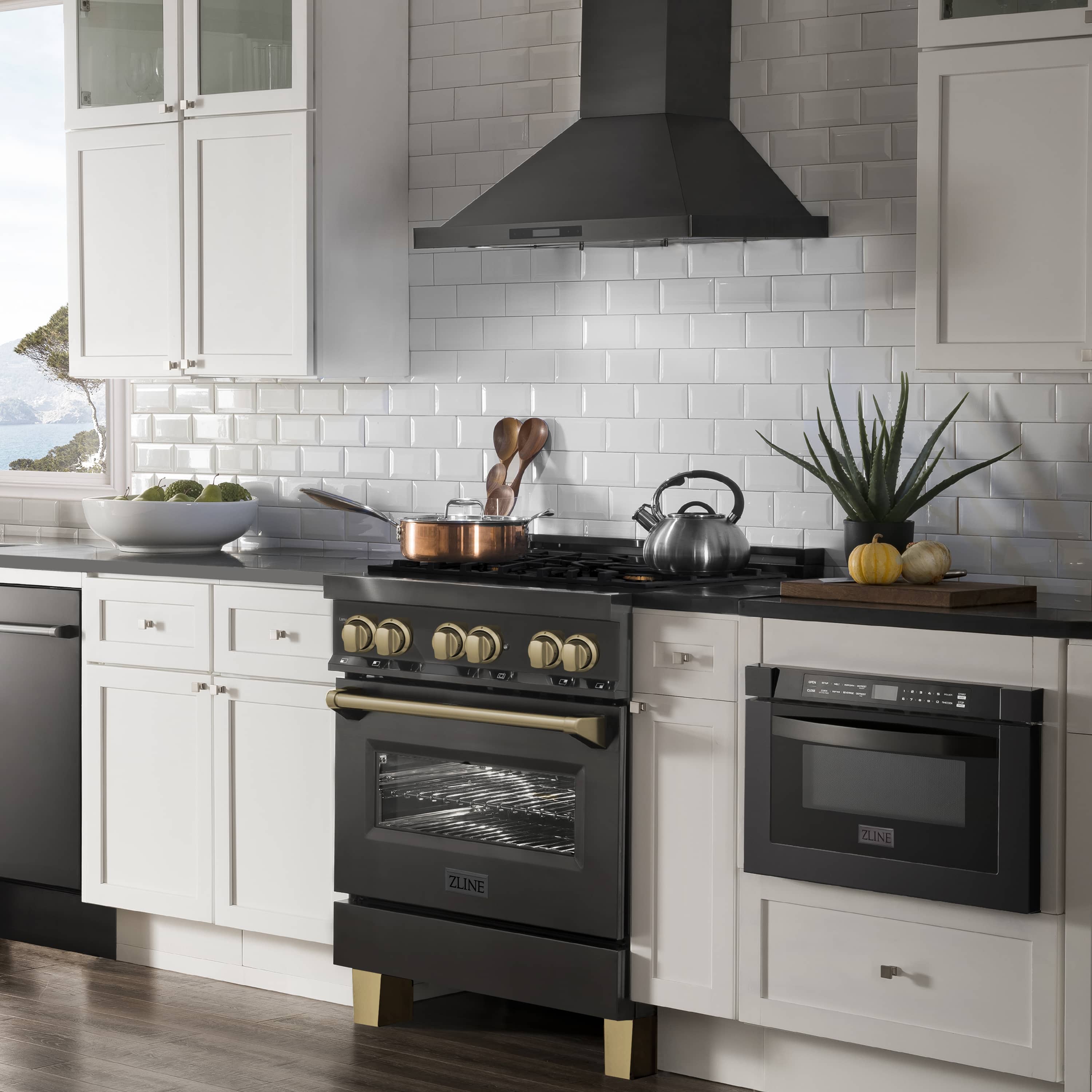Black dual fuel range with gold knobs, oven door, and stainless cooktop hood