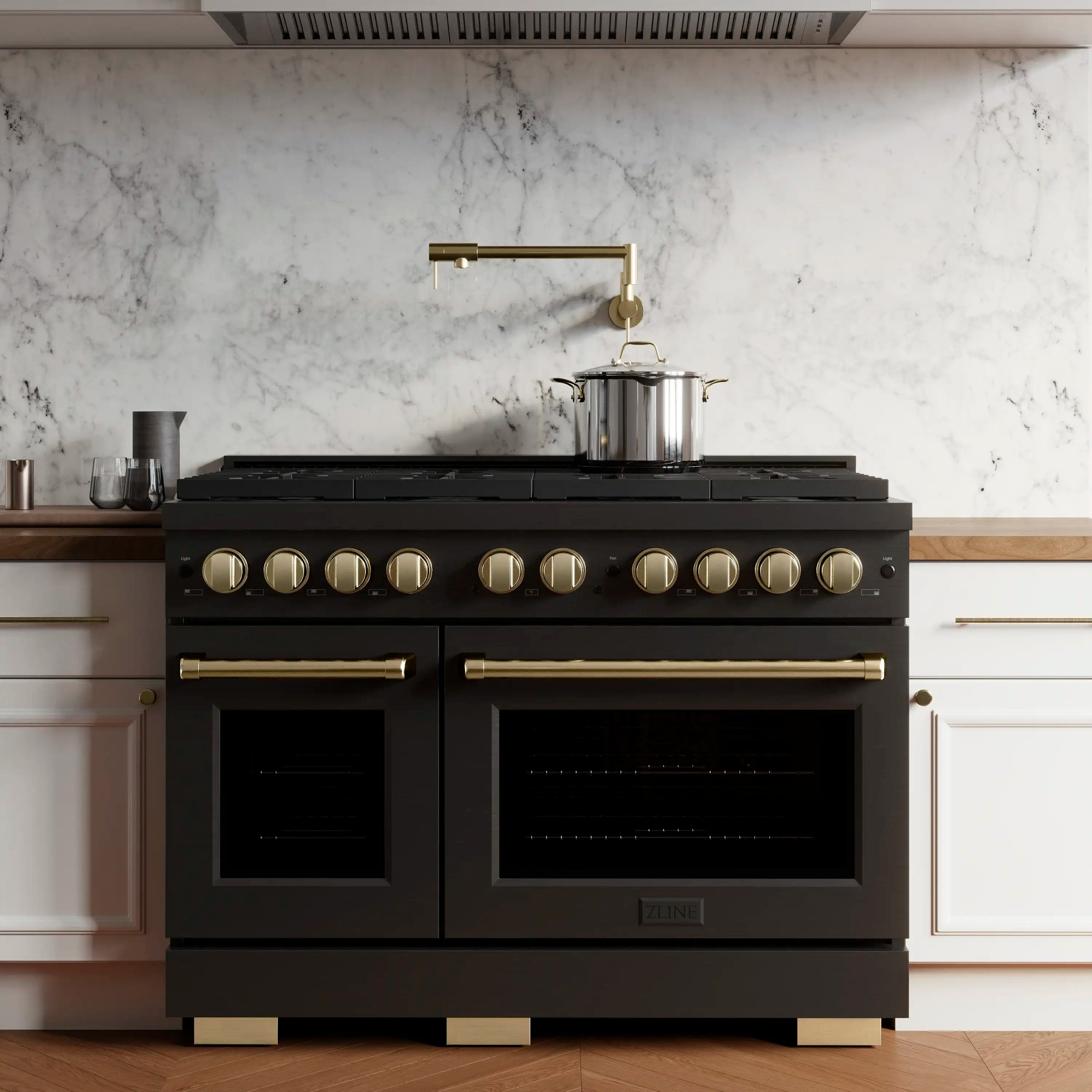 Black double-oven dual-fuel range with champagne bronze controls, handles, and cooktop burners