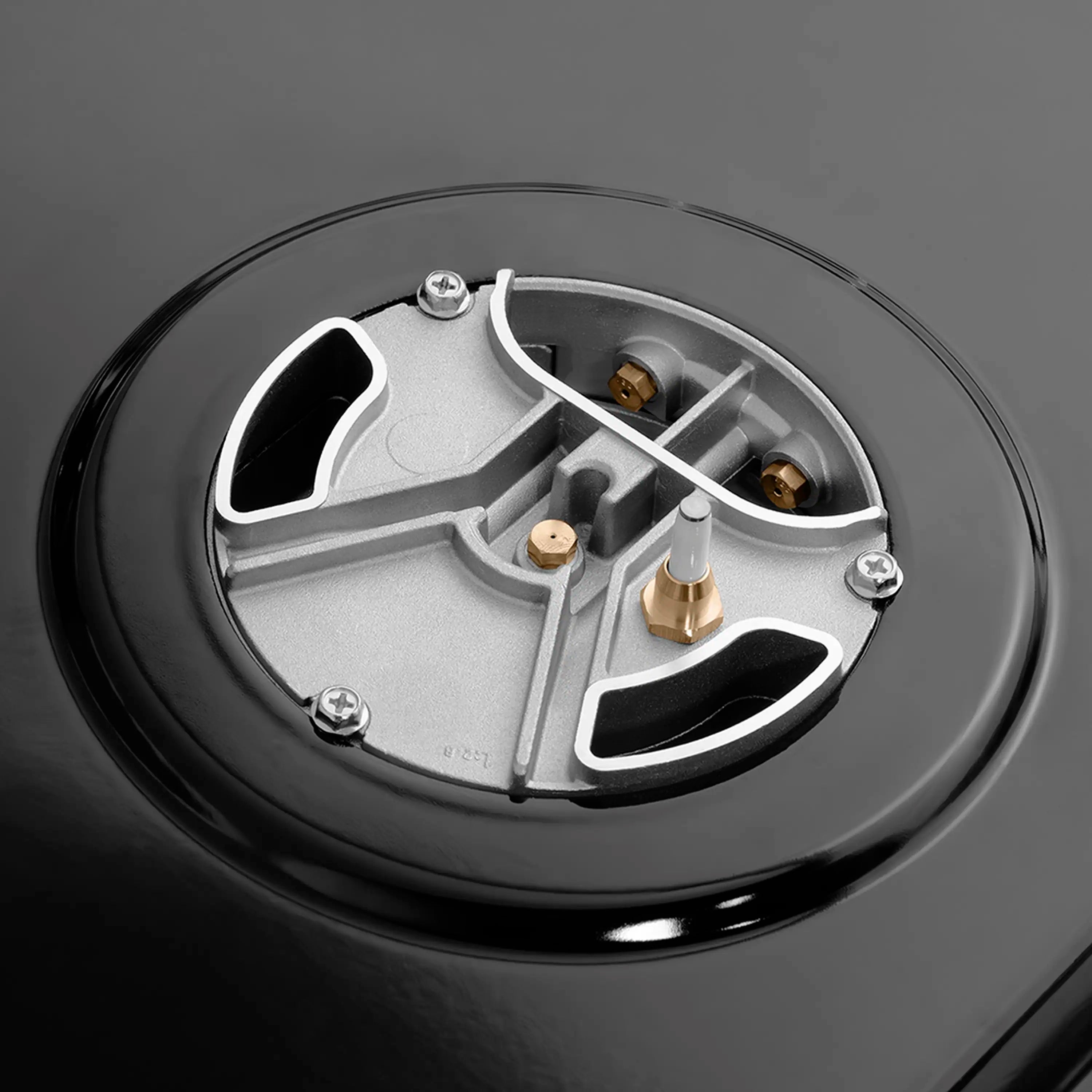 Gas burner cap assembly with metallic igniter parts on a black cooktop