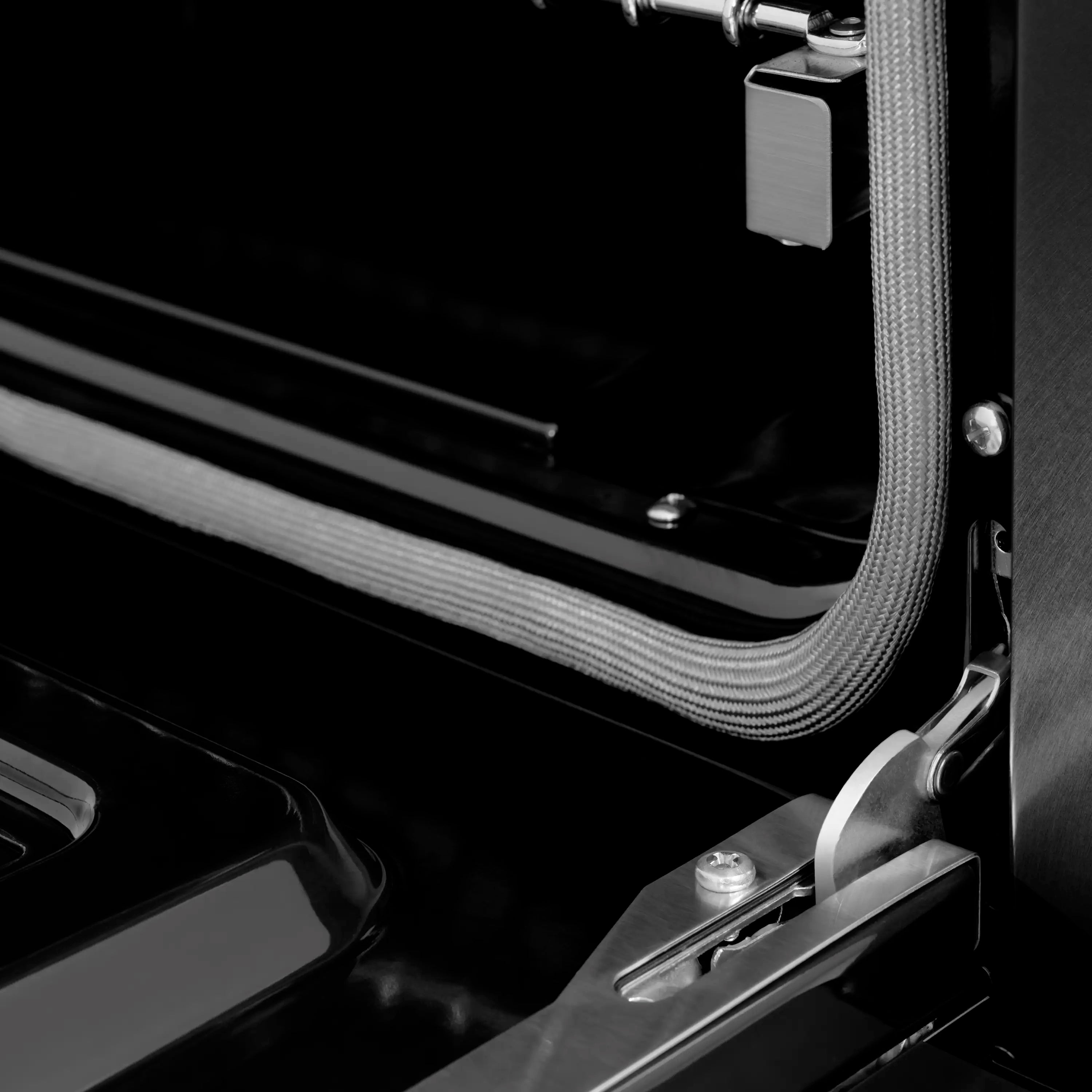 Close-up of oven door handle and black side trim with metal accents