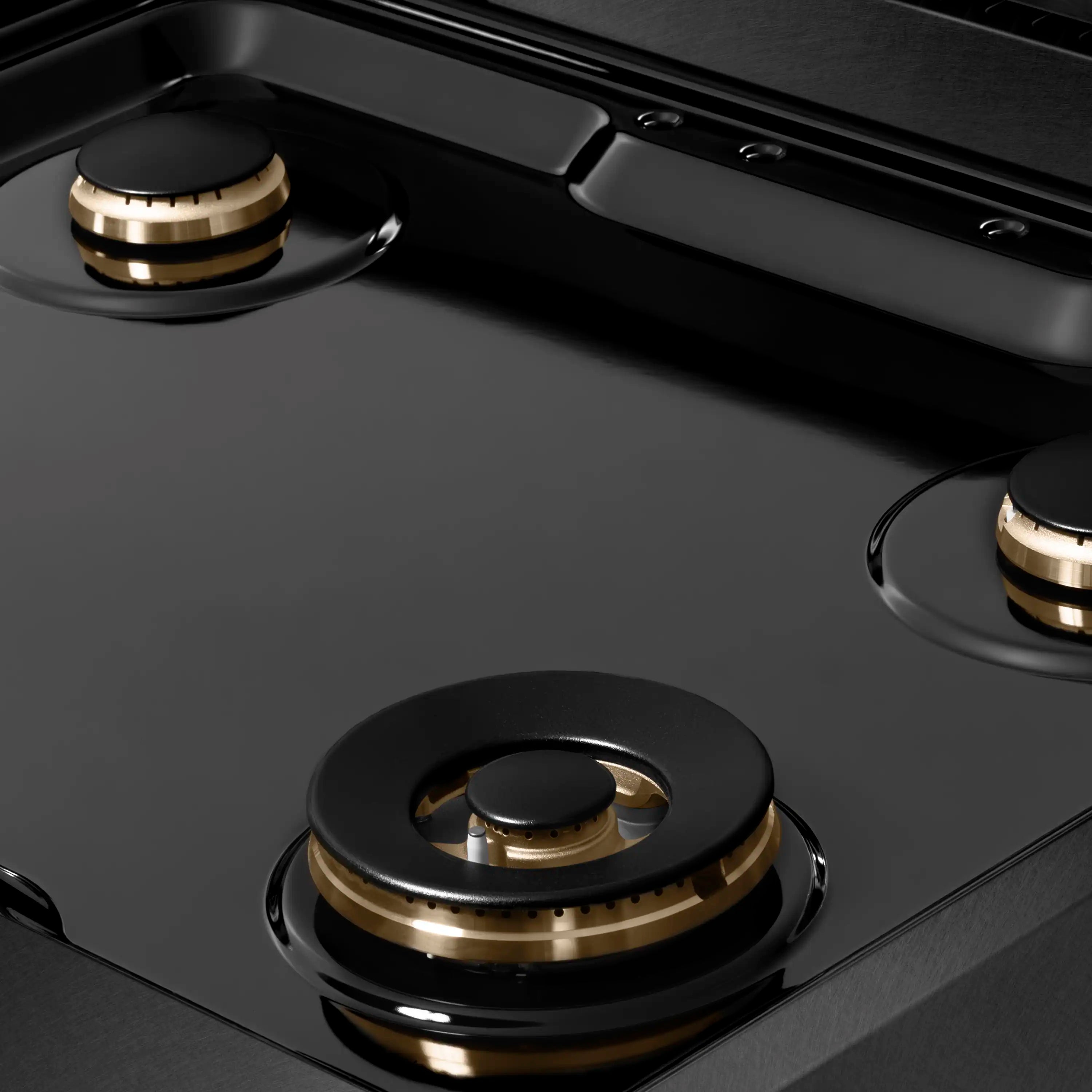 Close-up of black grate and champagne bronze burner base on a black satin cooktop