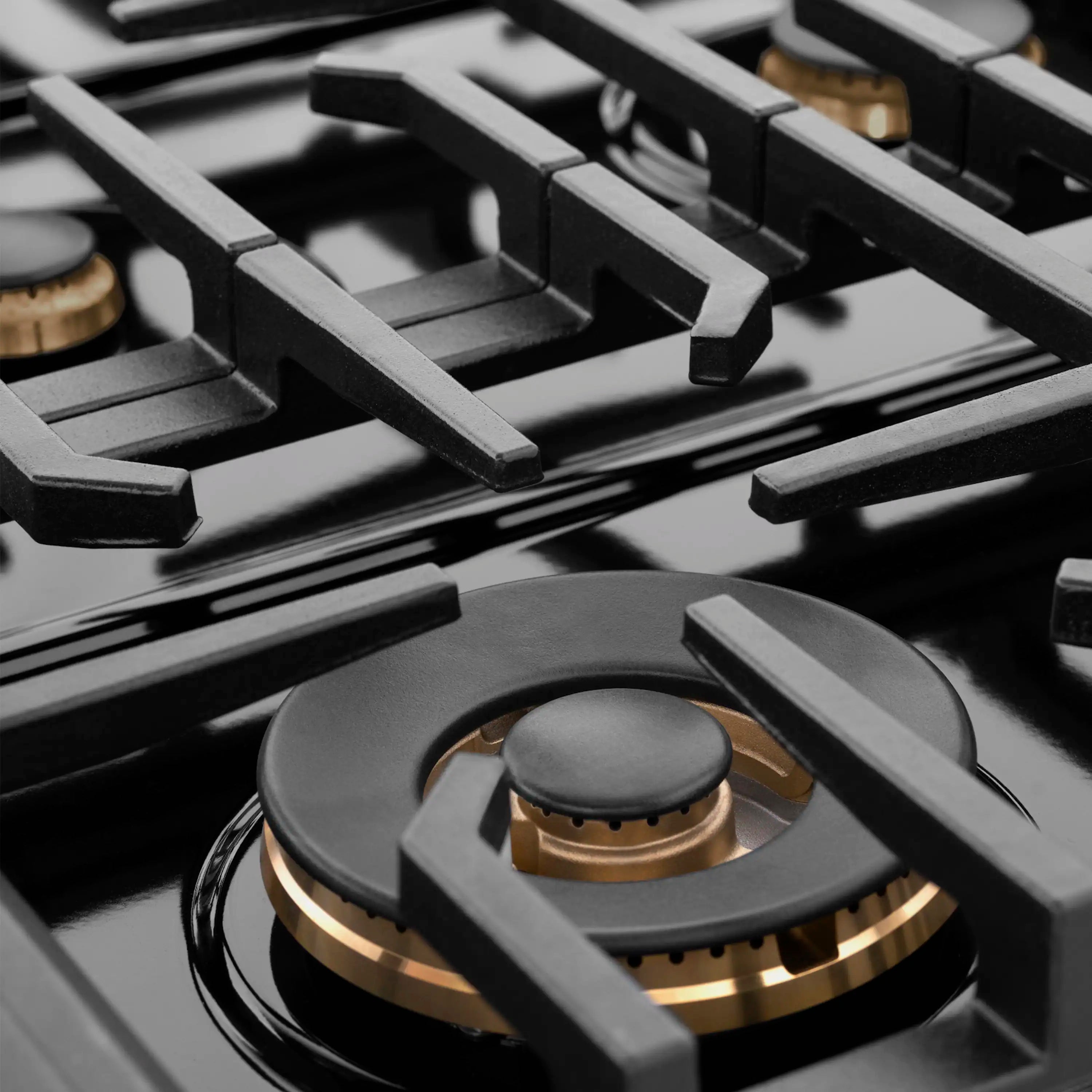 Black burner grate and burner head with gold accents on the cooktop