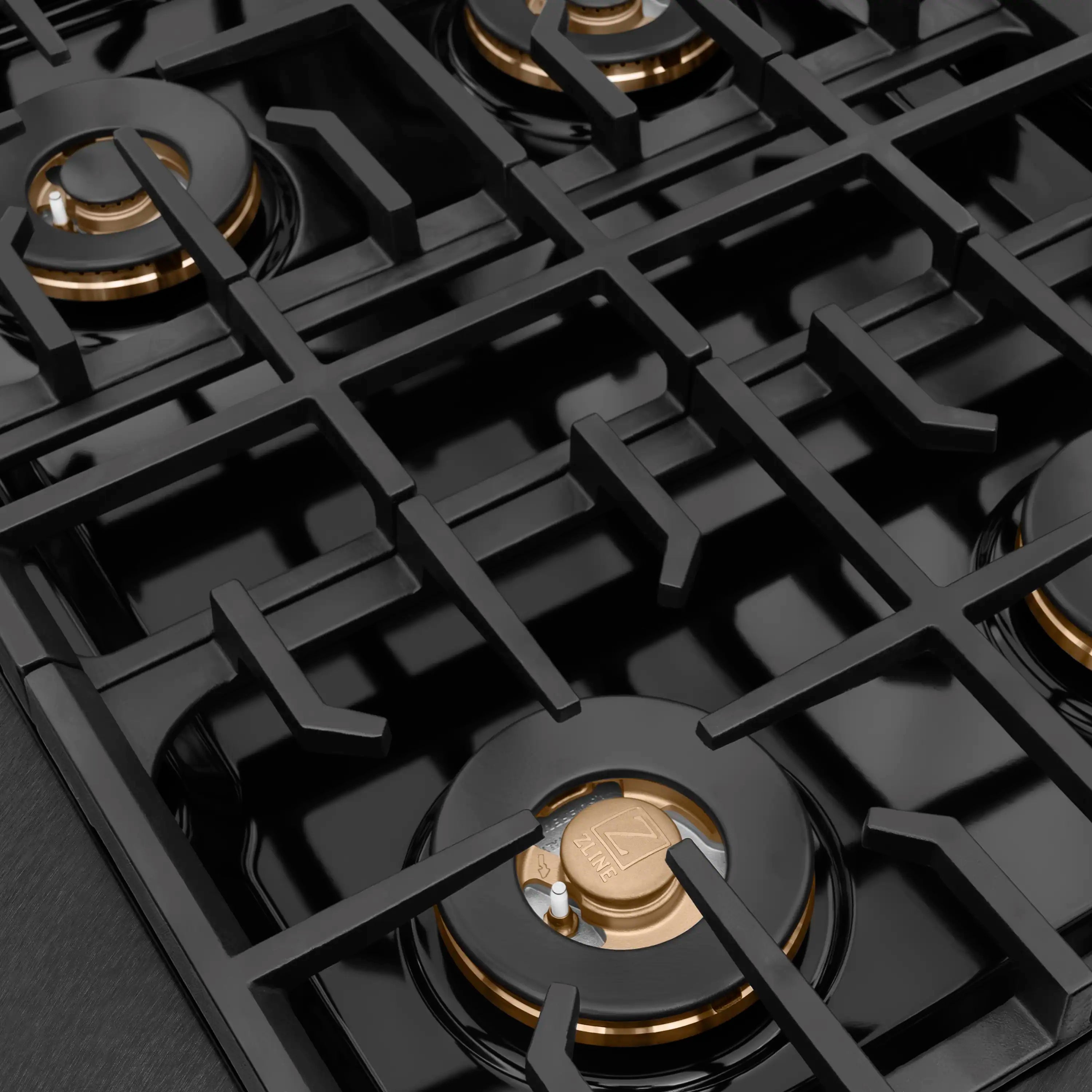 Close-up of black burner grates with brass gas ports and burner heads
