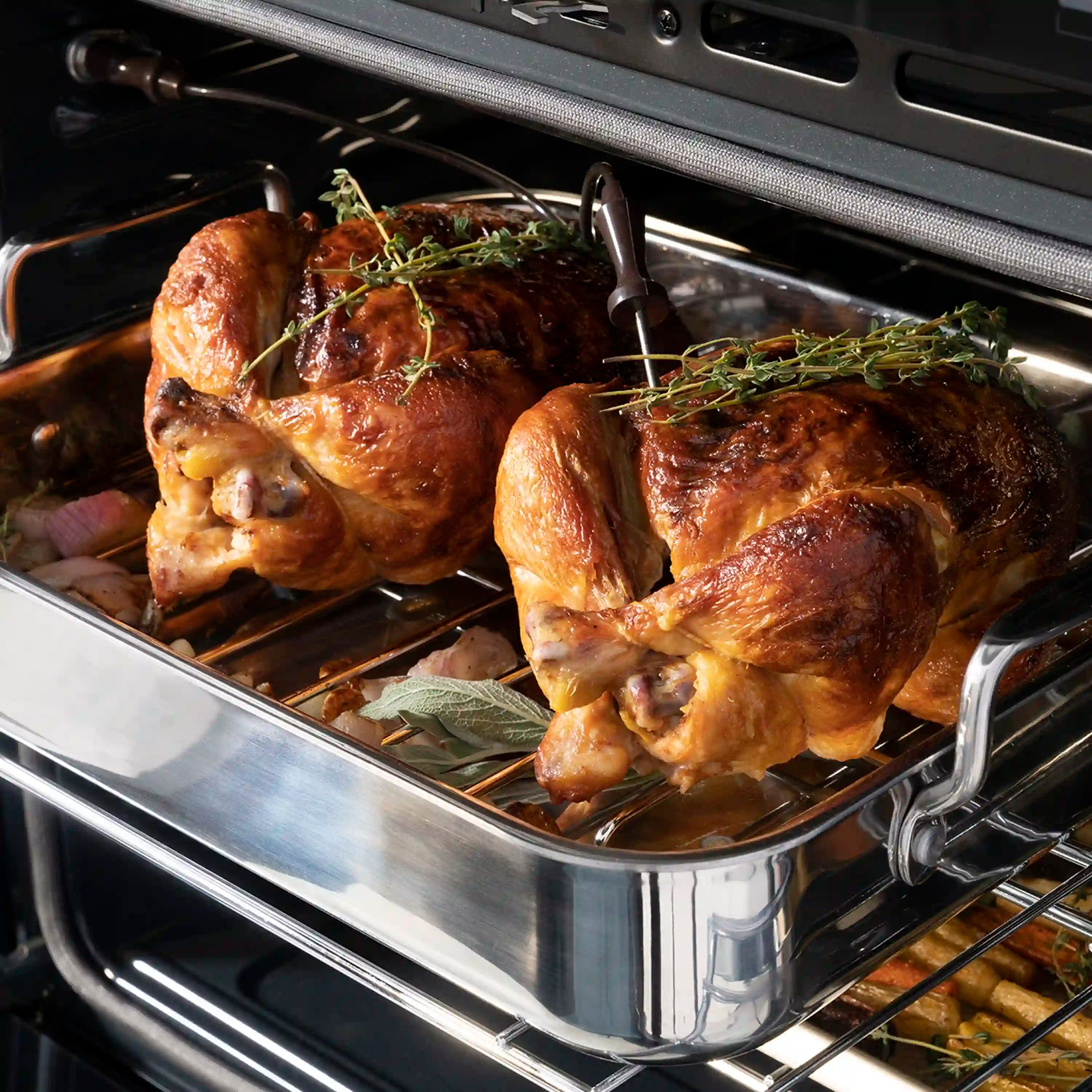 Stainless oven interior with multiple roasted chickens on wire racks