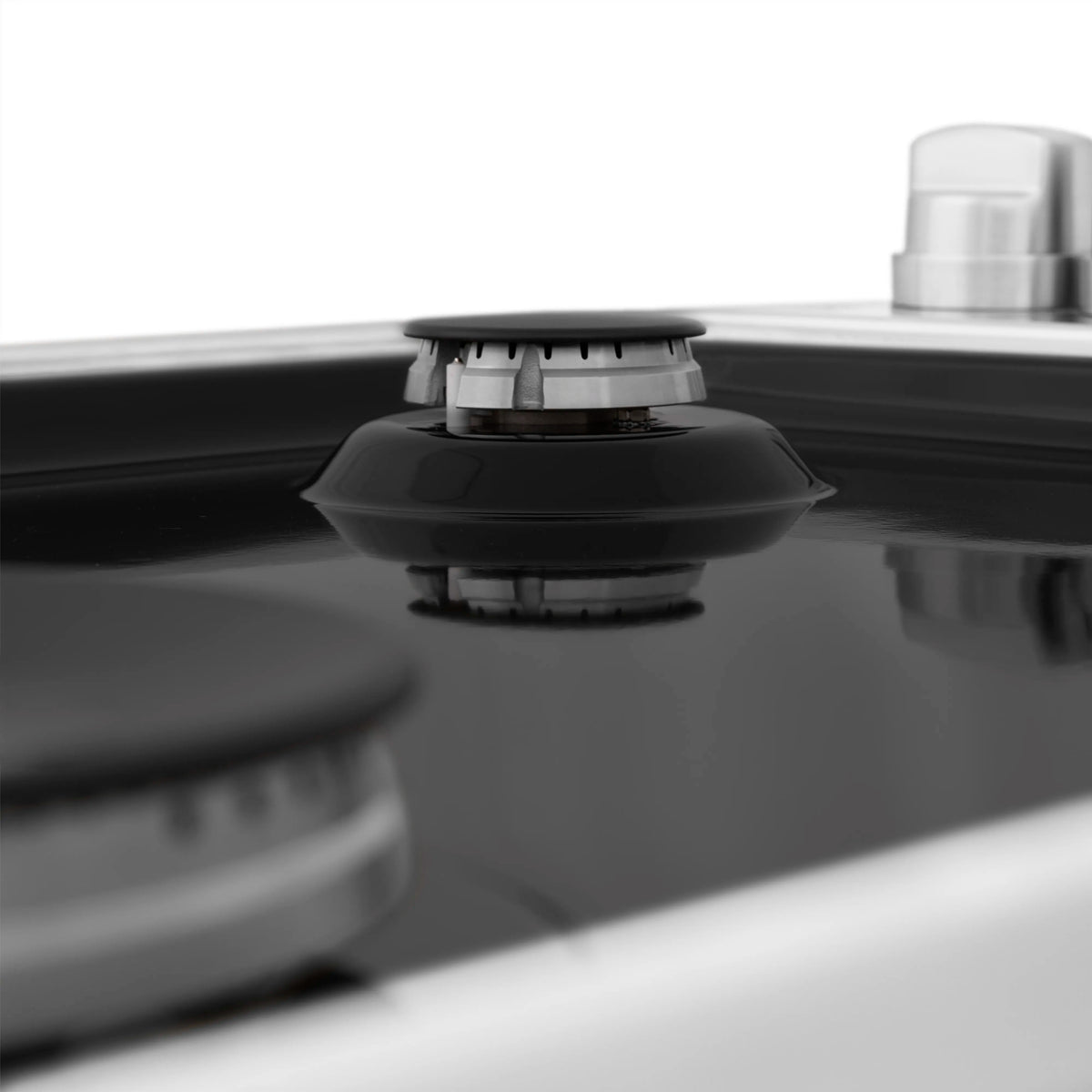 Black gas burner cap on a black porcelain cooktop surface