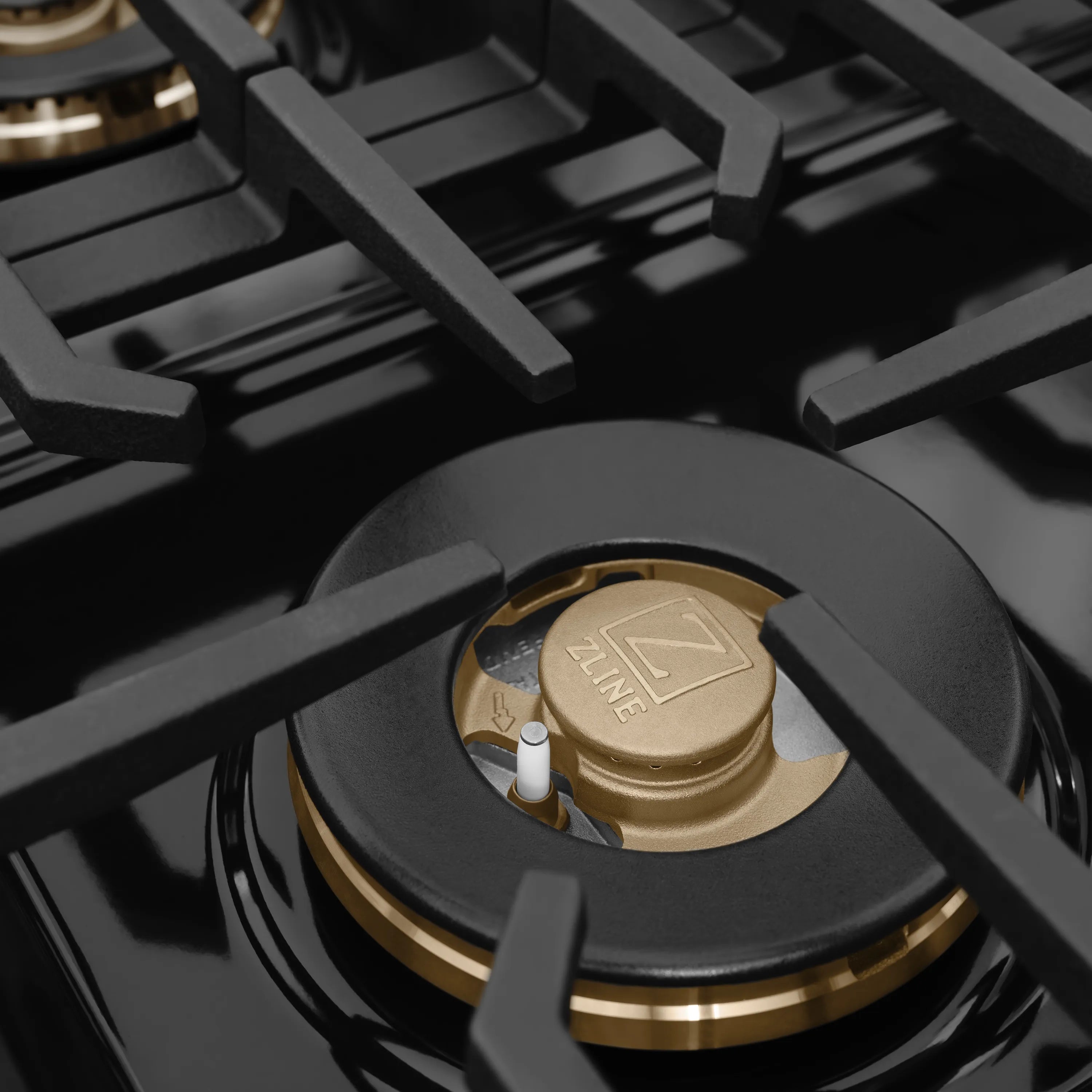 Gas burner cap and grates with gold center on a dark cooktop surface