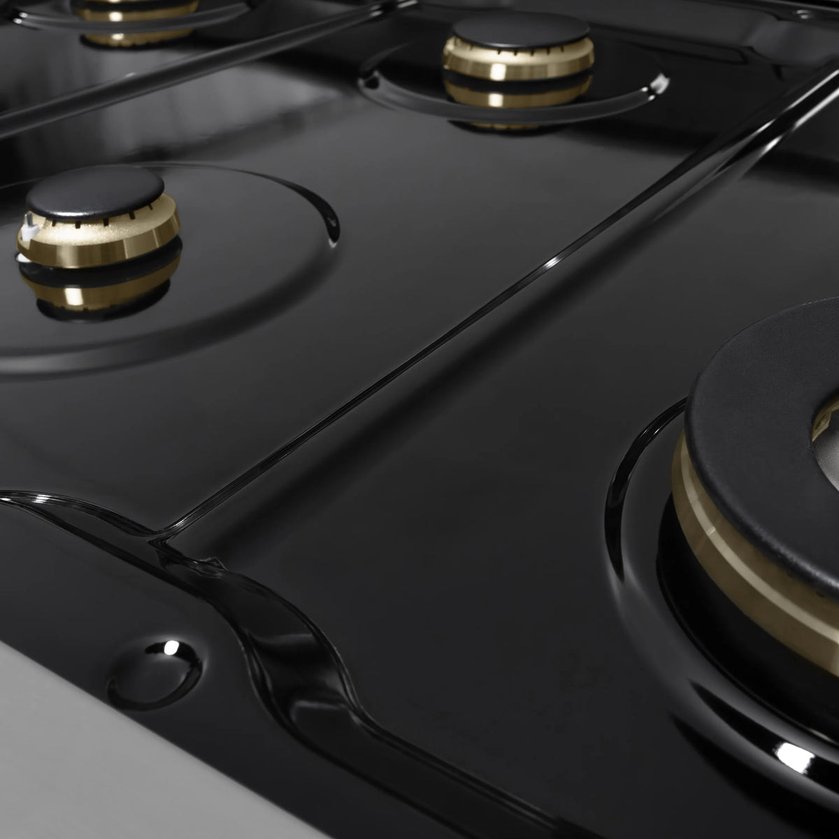 Matte black gas cooktop with brass-accent burner caps and round burner grates