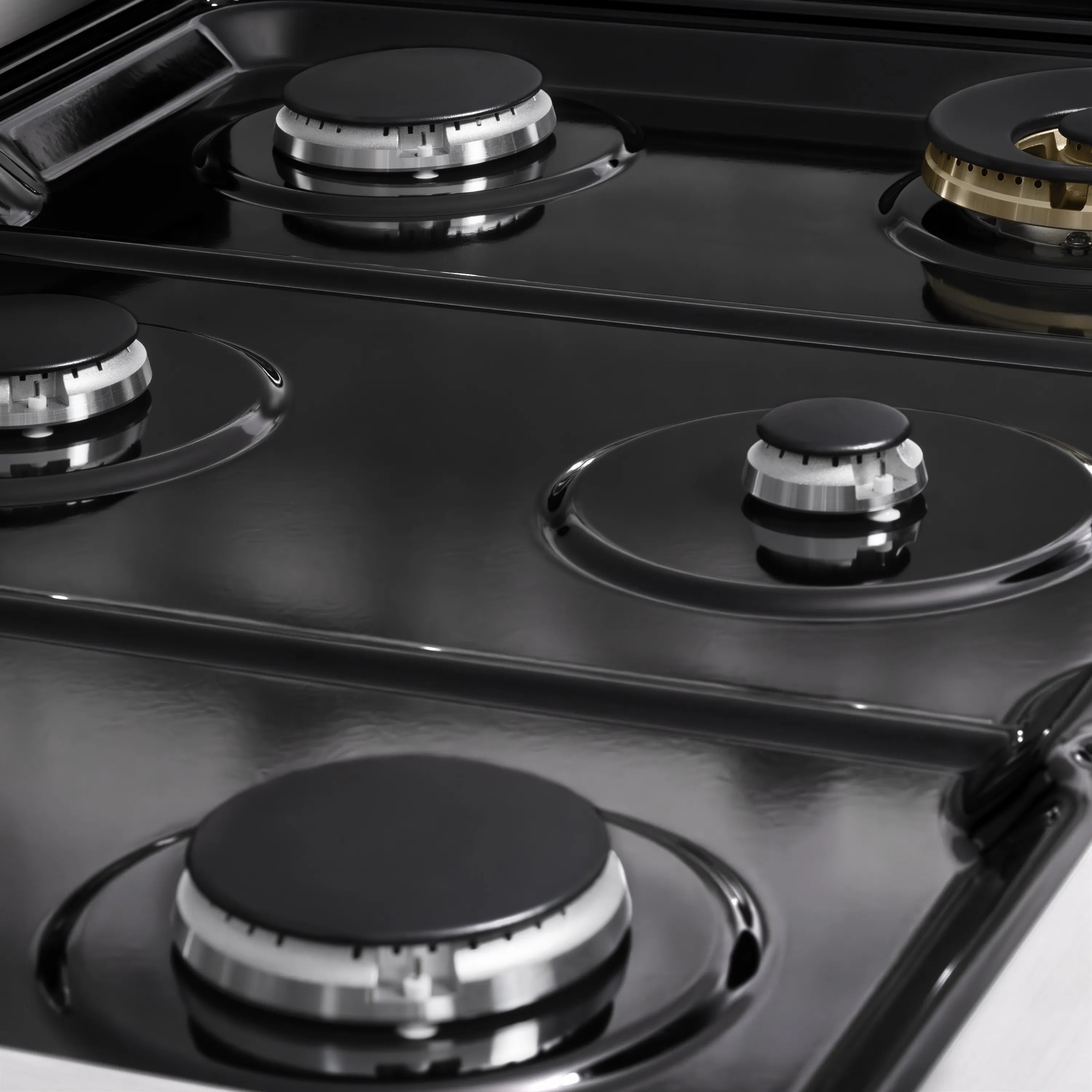 Close-up of black gas cooktop with four burner caps and metal grate sections