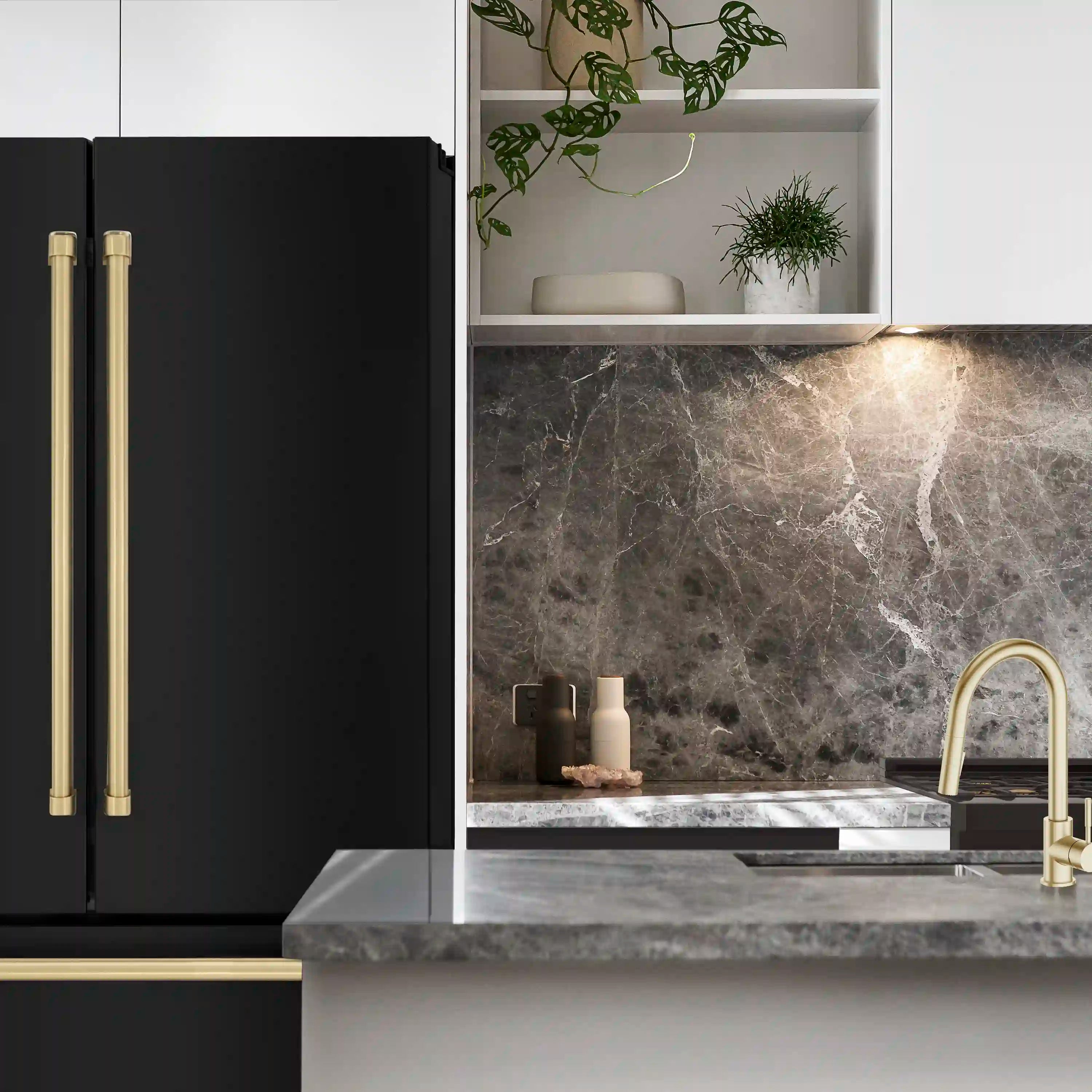 Black refrigerator with champagne bronze handle bars beside kitchen sink