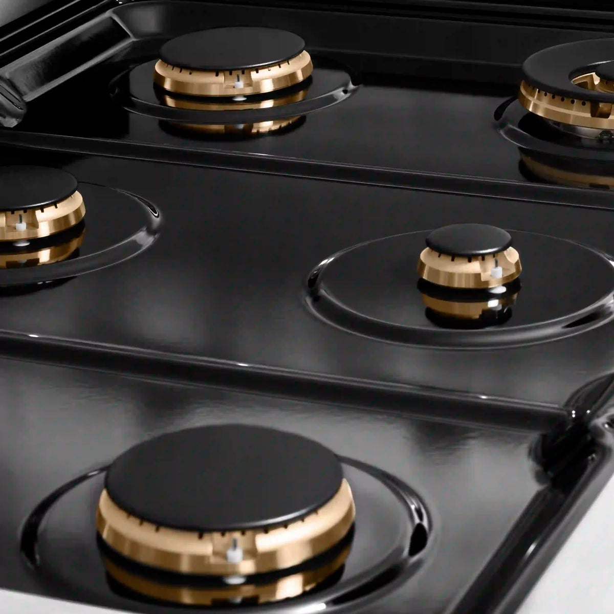 Stainless steel dual fuel range cooktop with four black burner caps and gold ring knobs