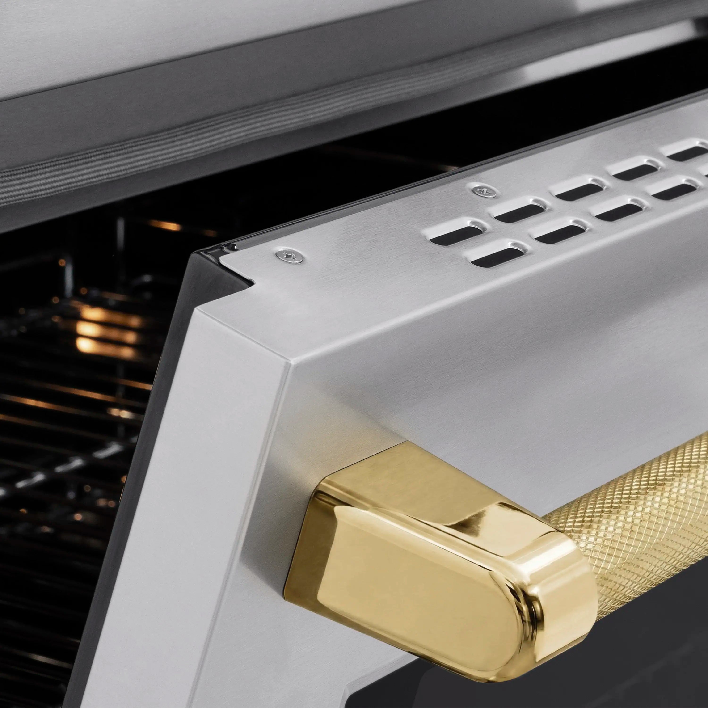 Gold helix oven handle on stainless steel door with black oven interior behind it.