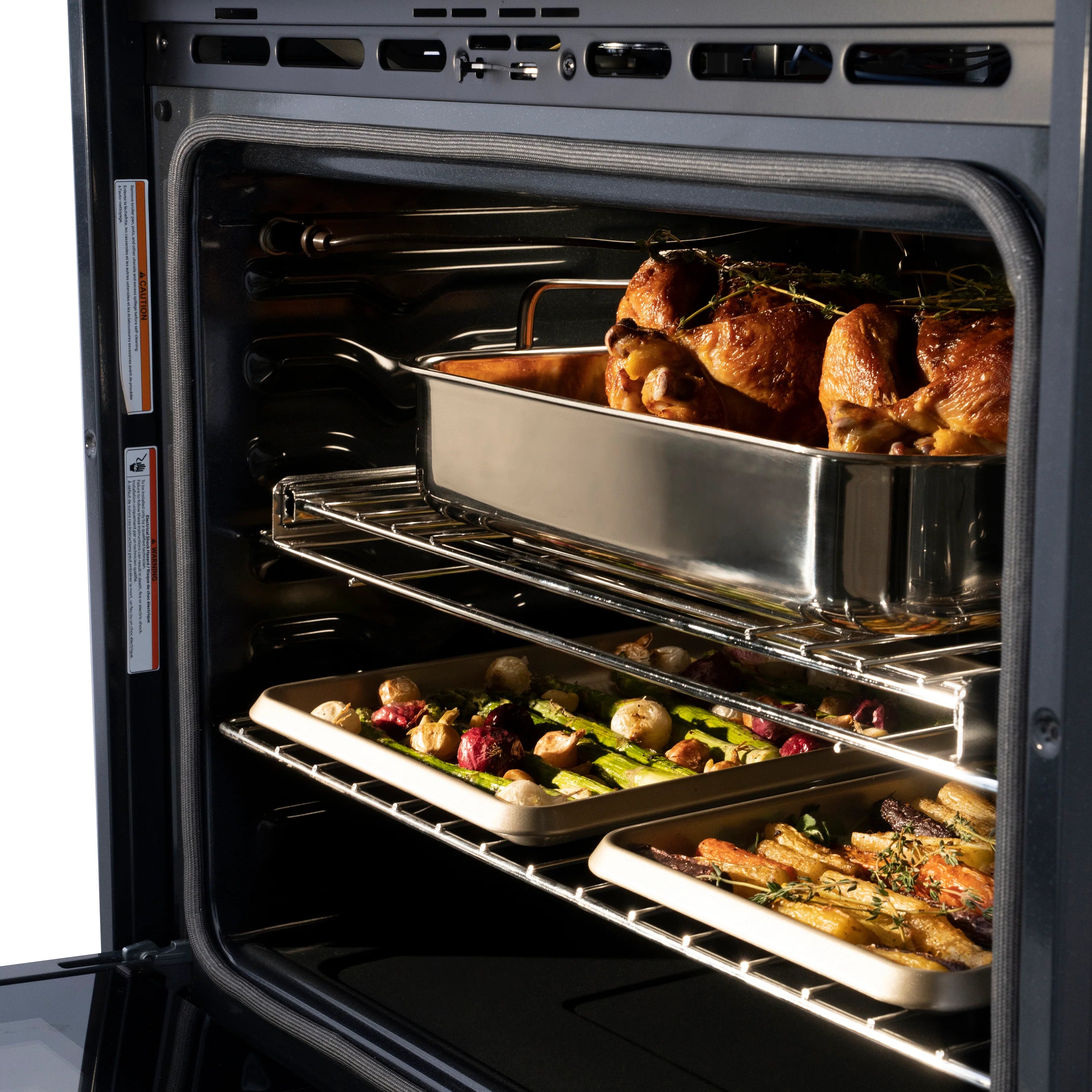 Multiple dishes and roasted food on oven racks in an electric double oven