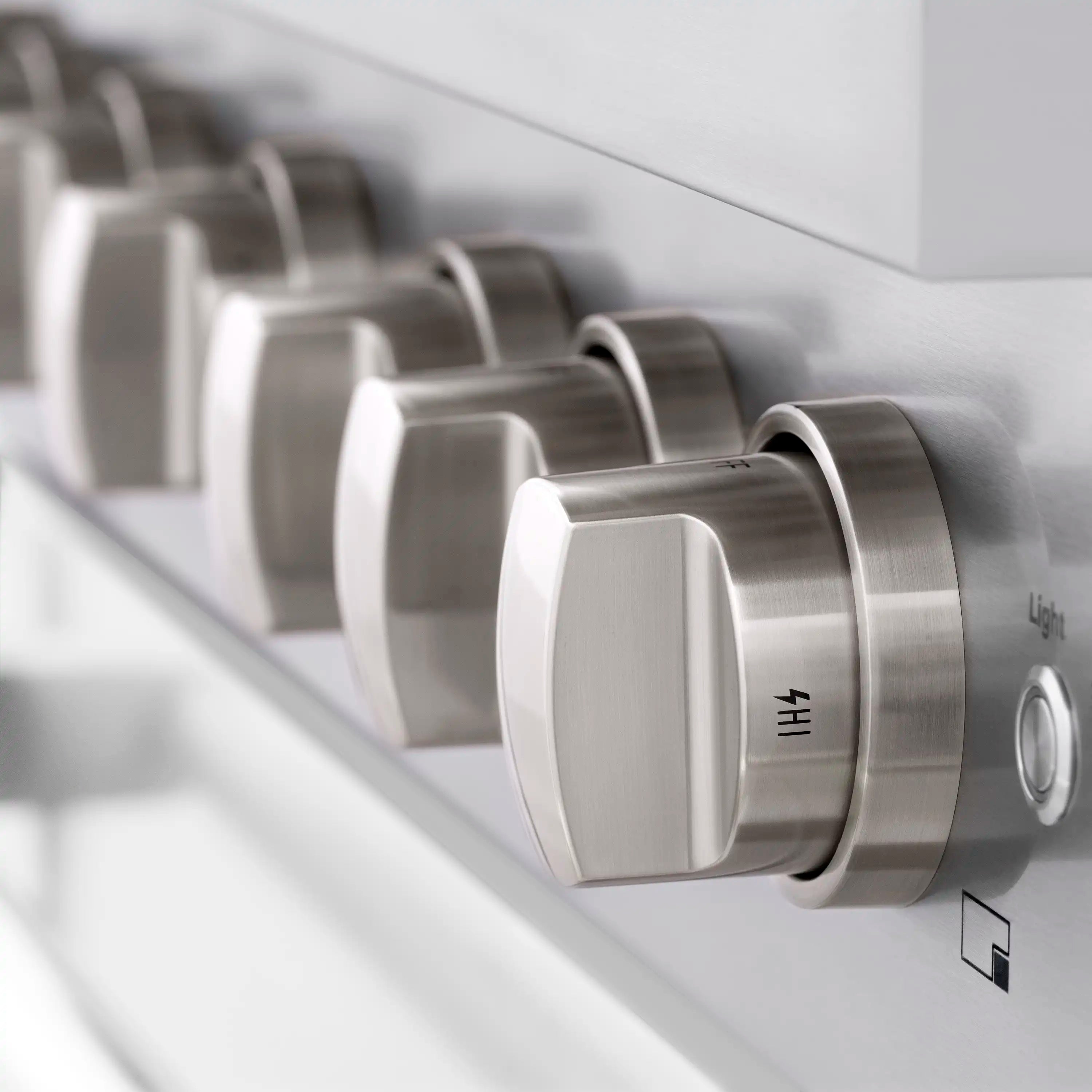 Stainless gas range control knobs with textured grip, side close-up