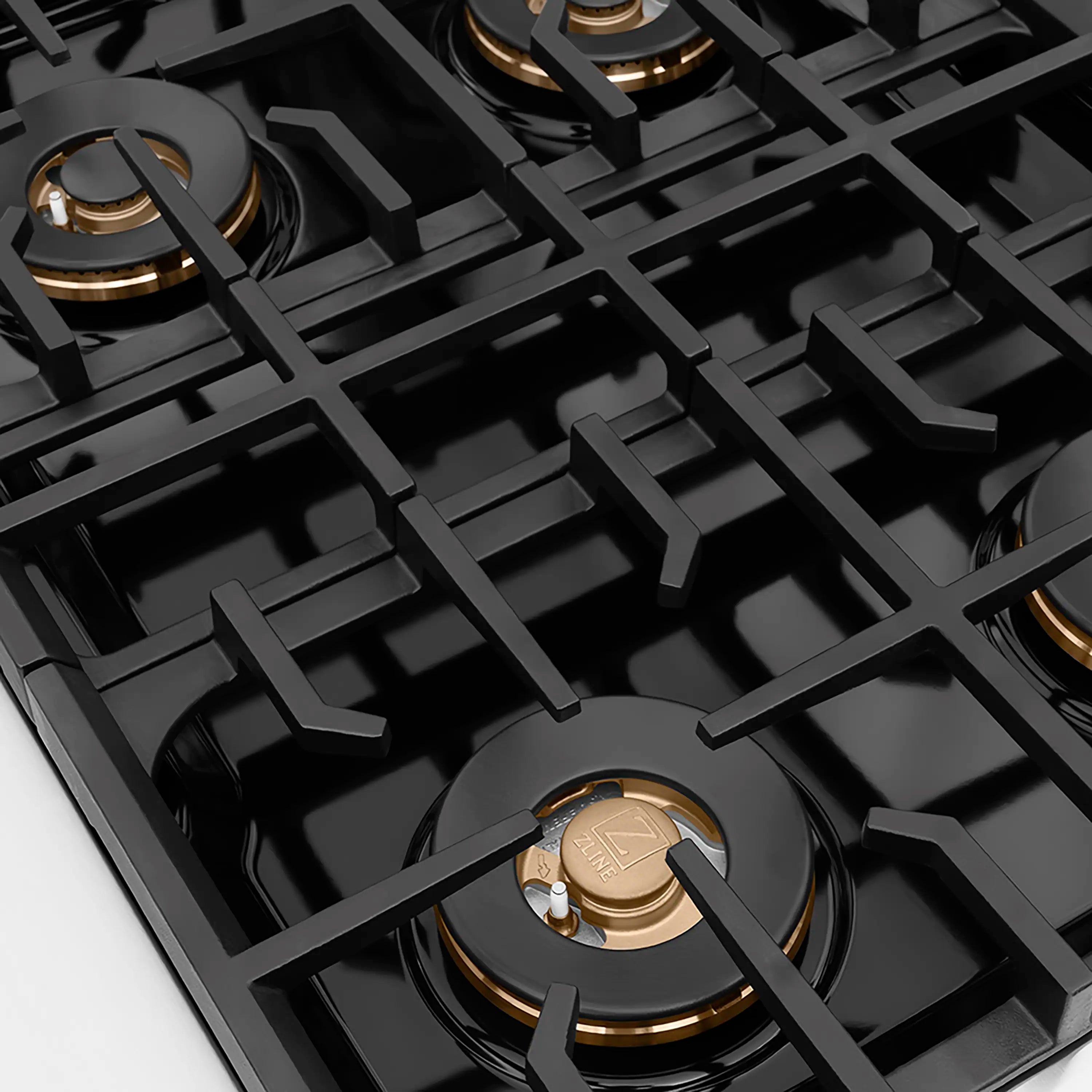 Gas cooktop grates with bronze-ring burner caps on a black stovetop surface