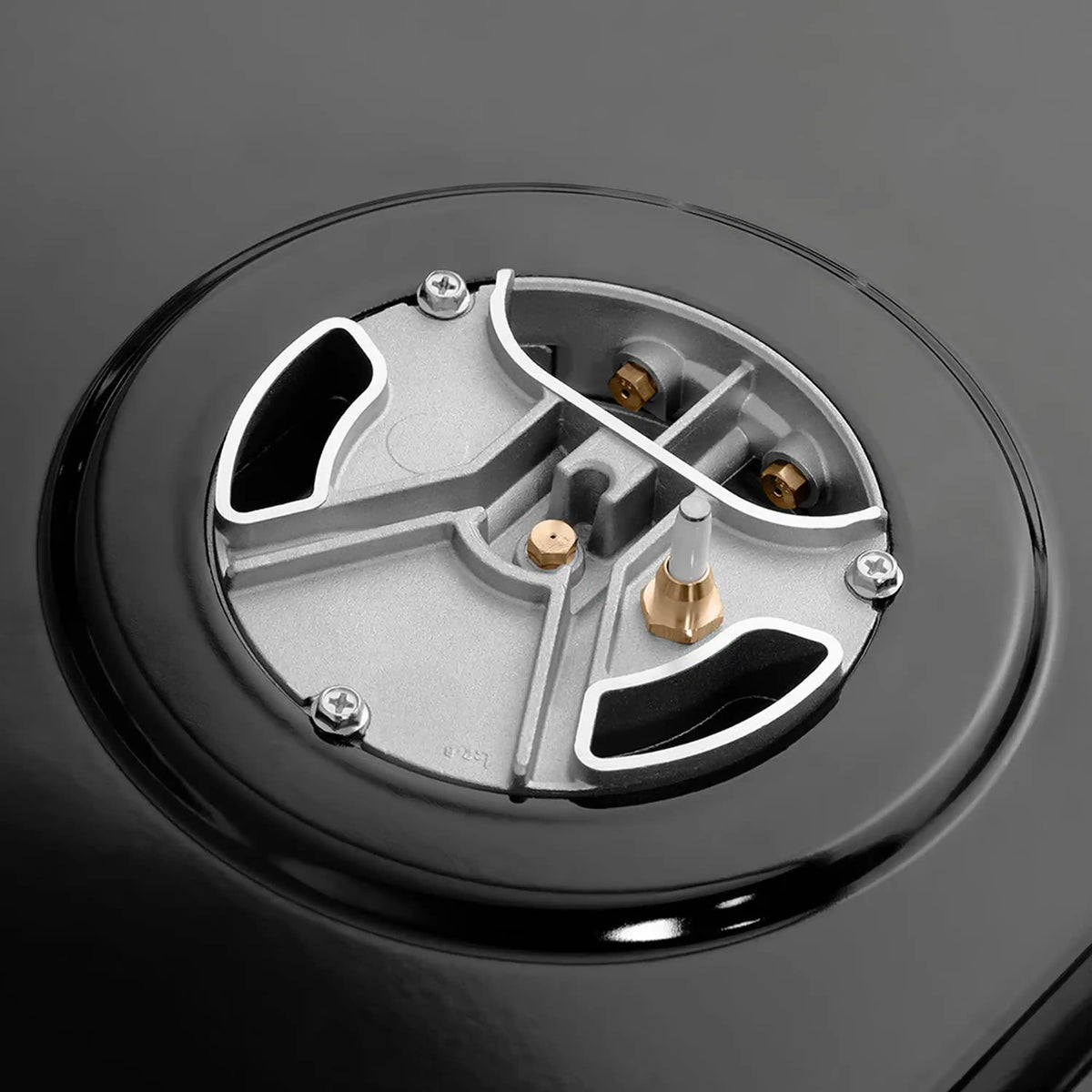 Black gas burner cap with brass ports and igniter screws on rangetop