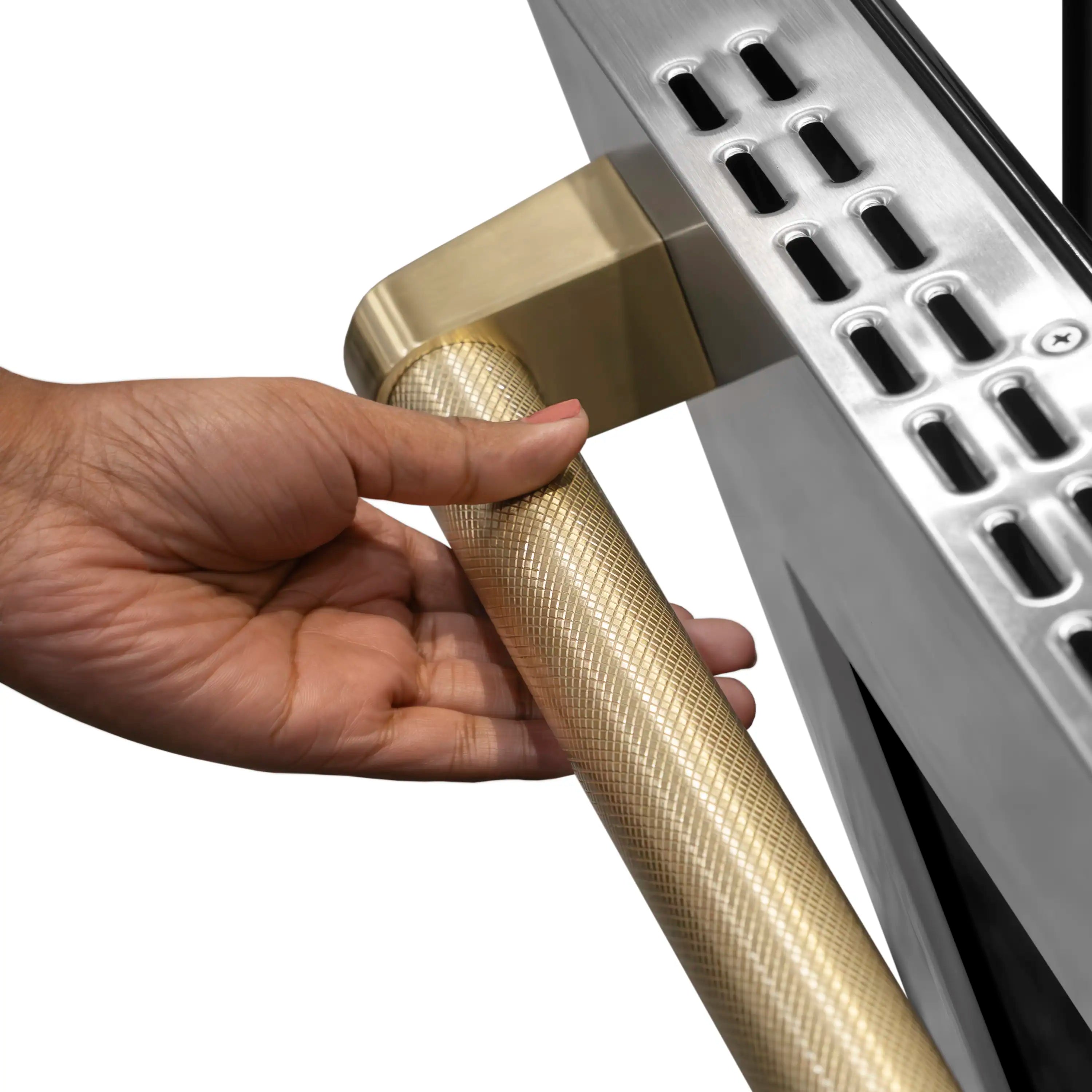 Hand holding champagne bronze textured handle on a stainless induction range