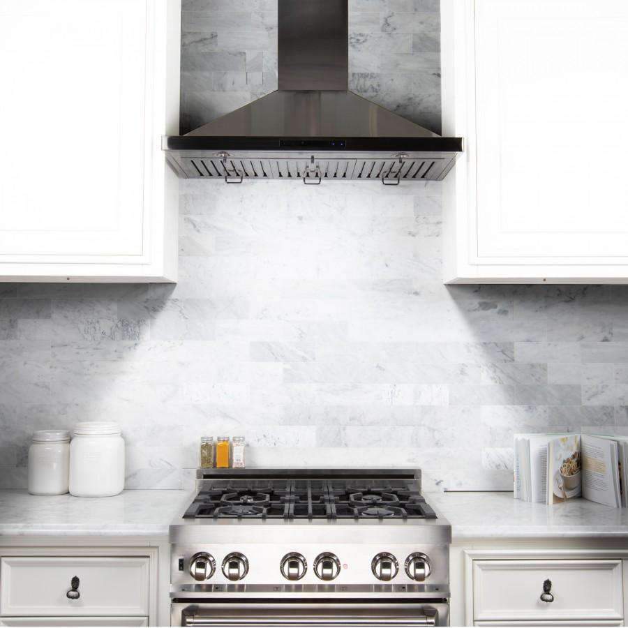 Black stainless steel range hood mounted over the cooktop in white cabinetry