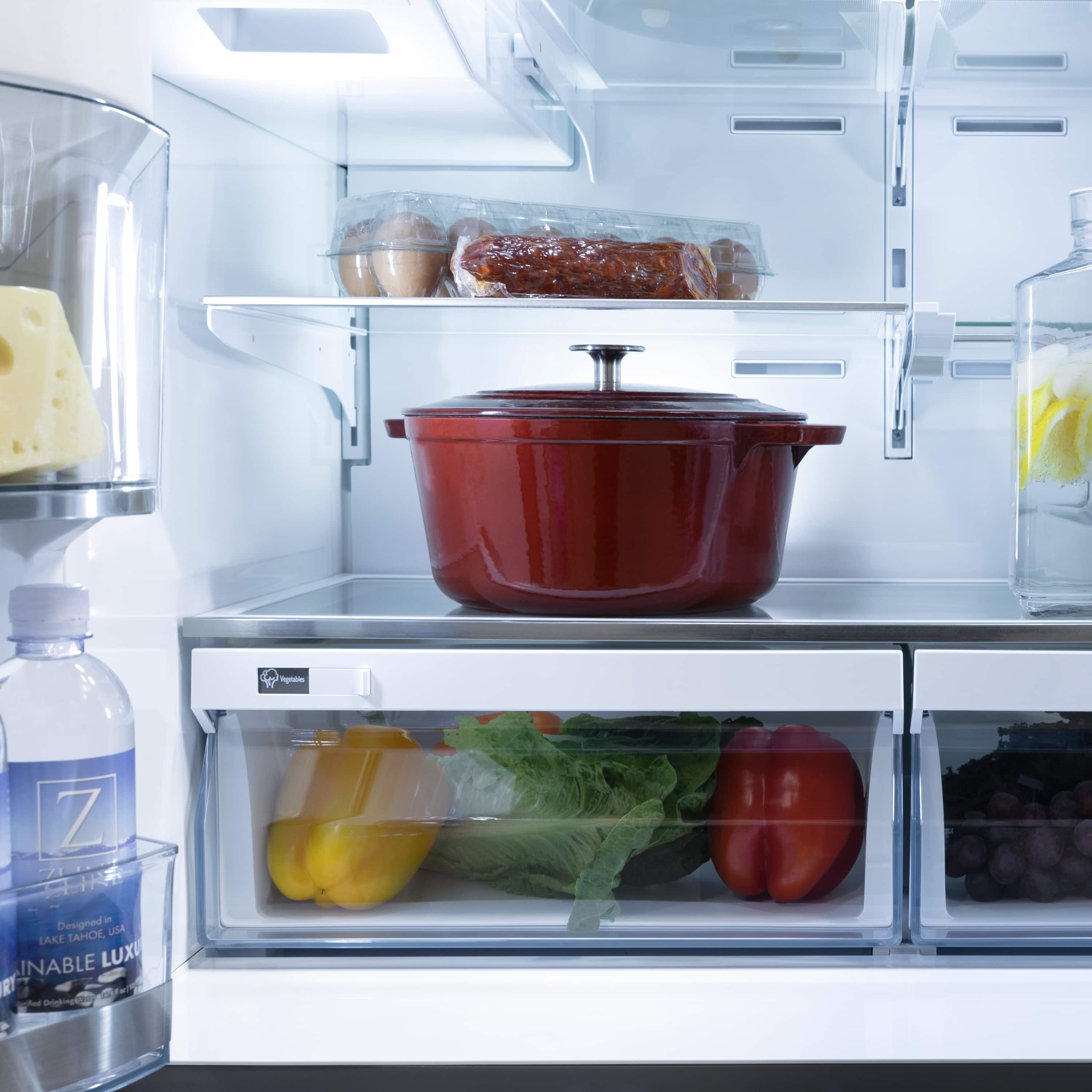 Refrigerator interior with glass shelves, vegetables, and covered storage containers