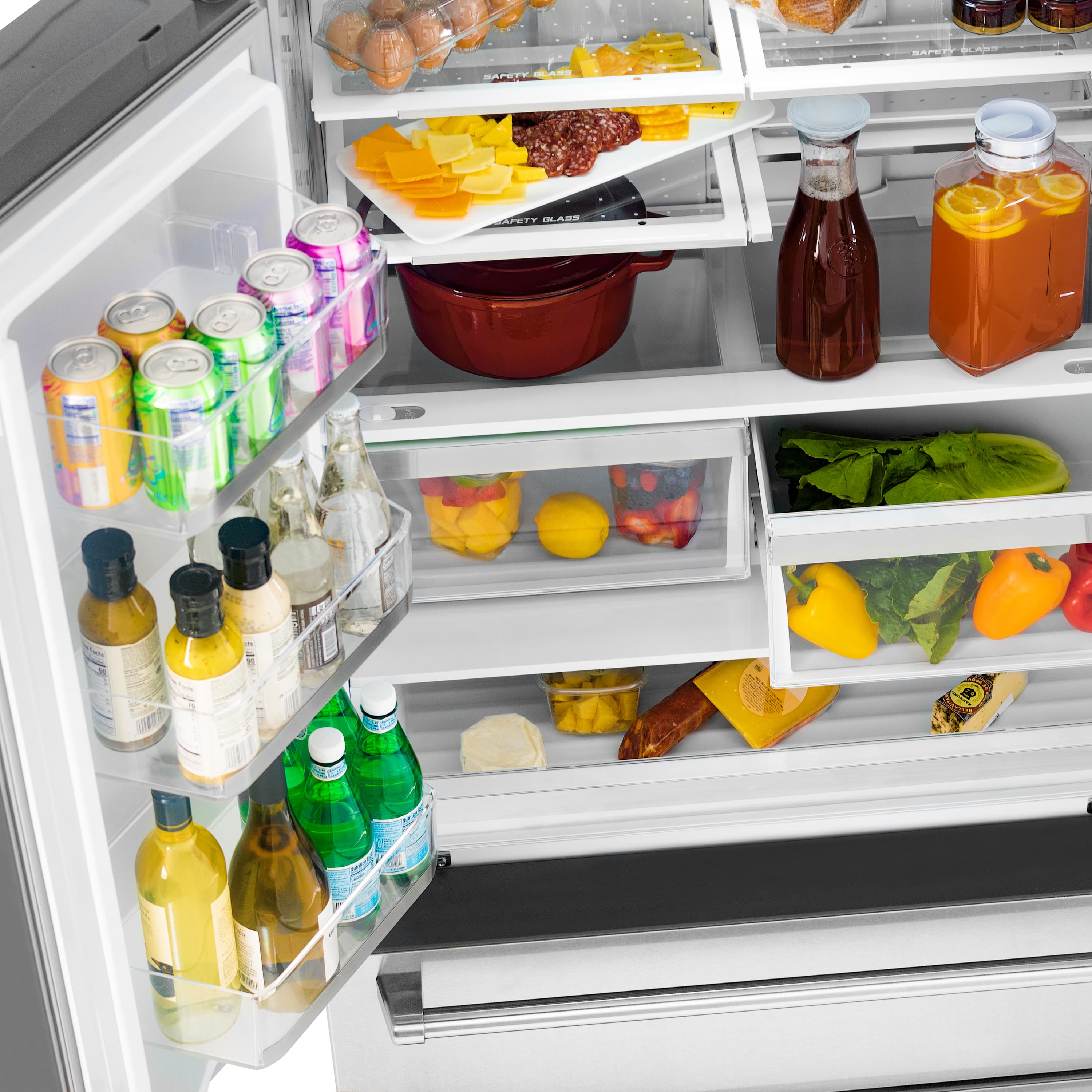 Stainless steel refrigerator drawer with bottles and packaged foods on shelves